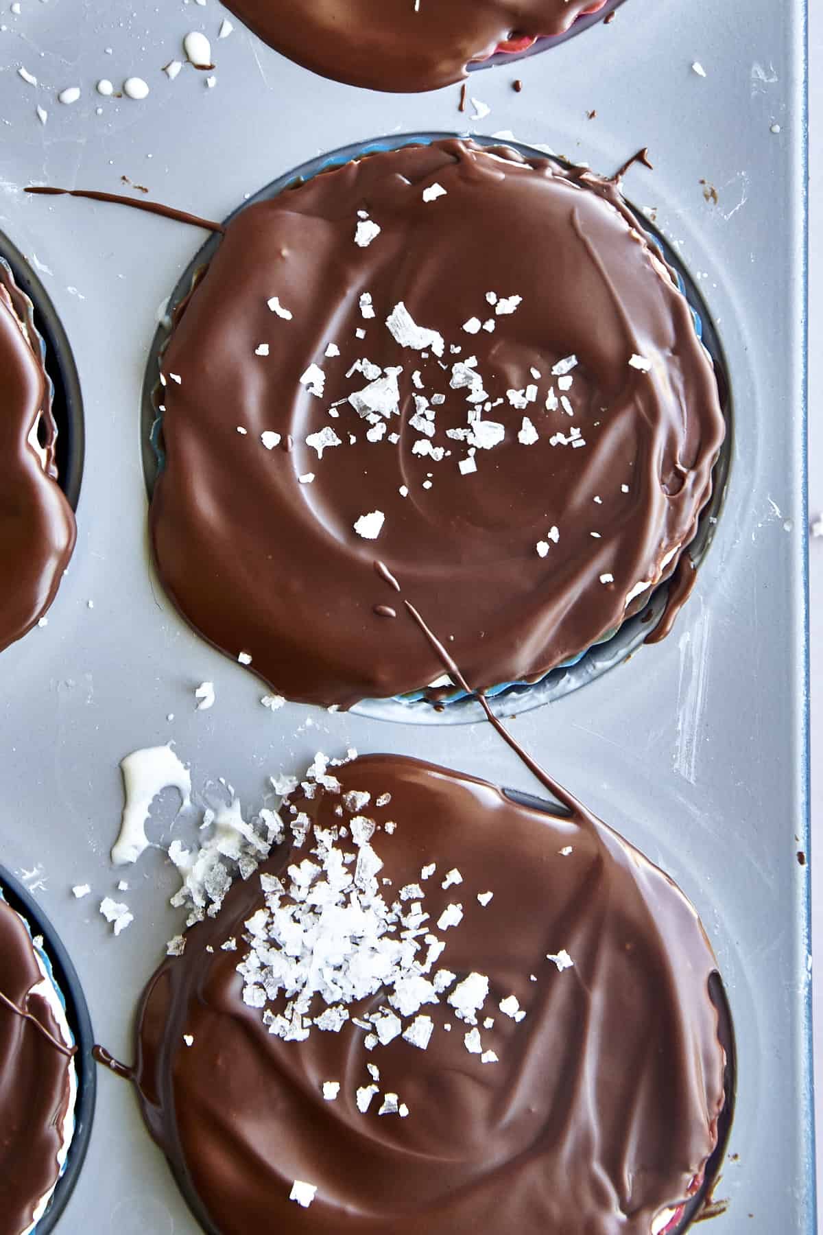 Chocolate coated frozen yogurt bites topped with se salt in a silicone-lined mini muffin tin.