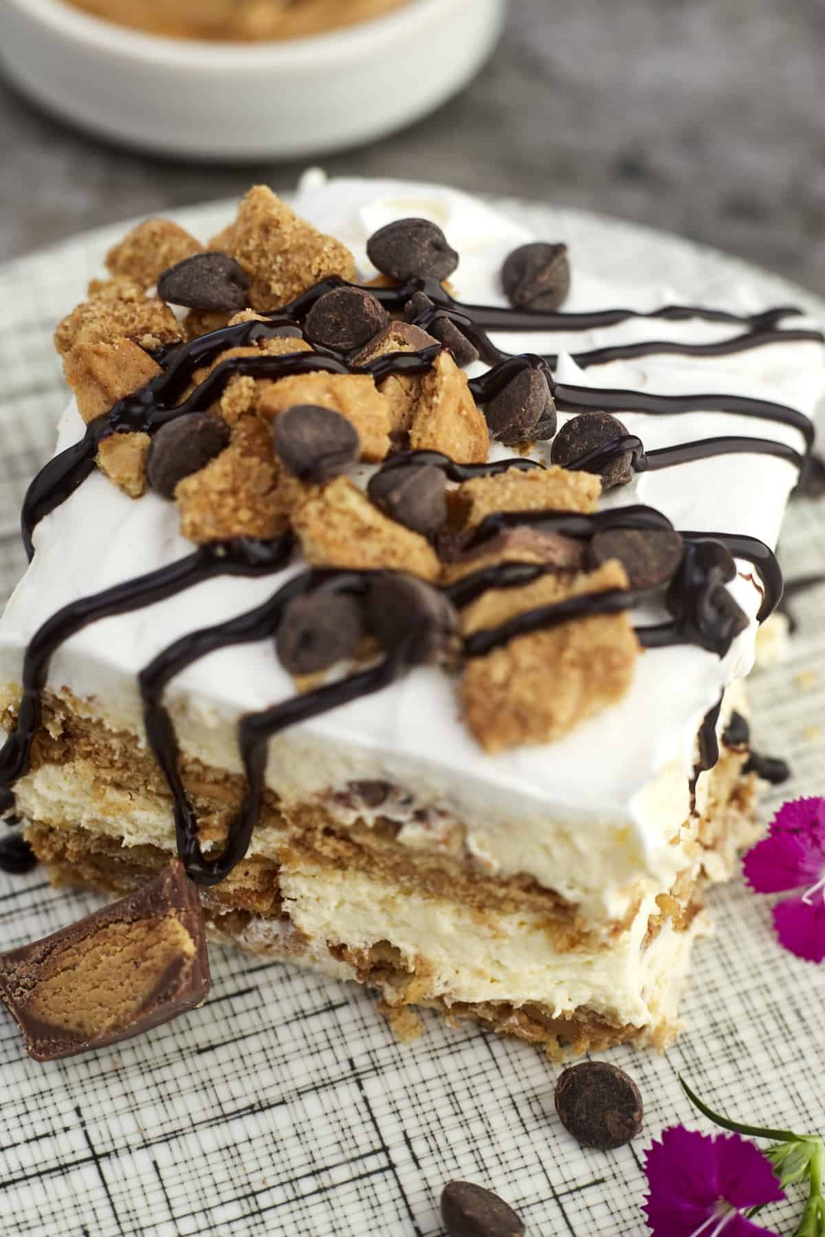a square of no-bake peanut butter lasagna with crushed Reese's, chocolate chips, and a drizzle of chocolate on top