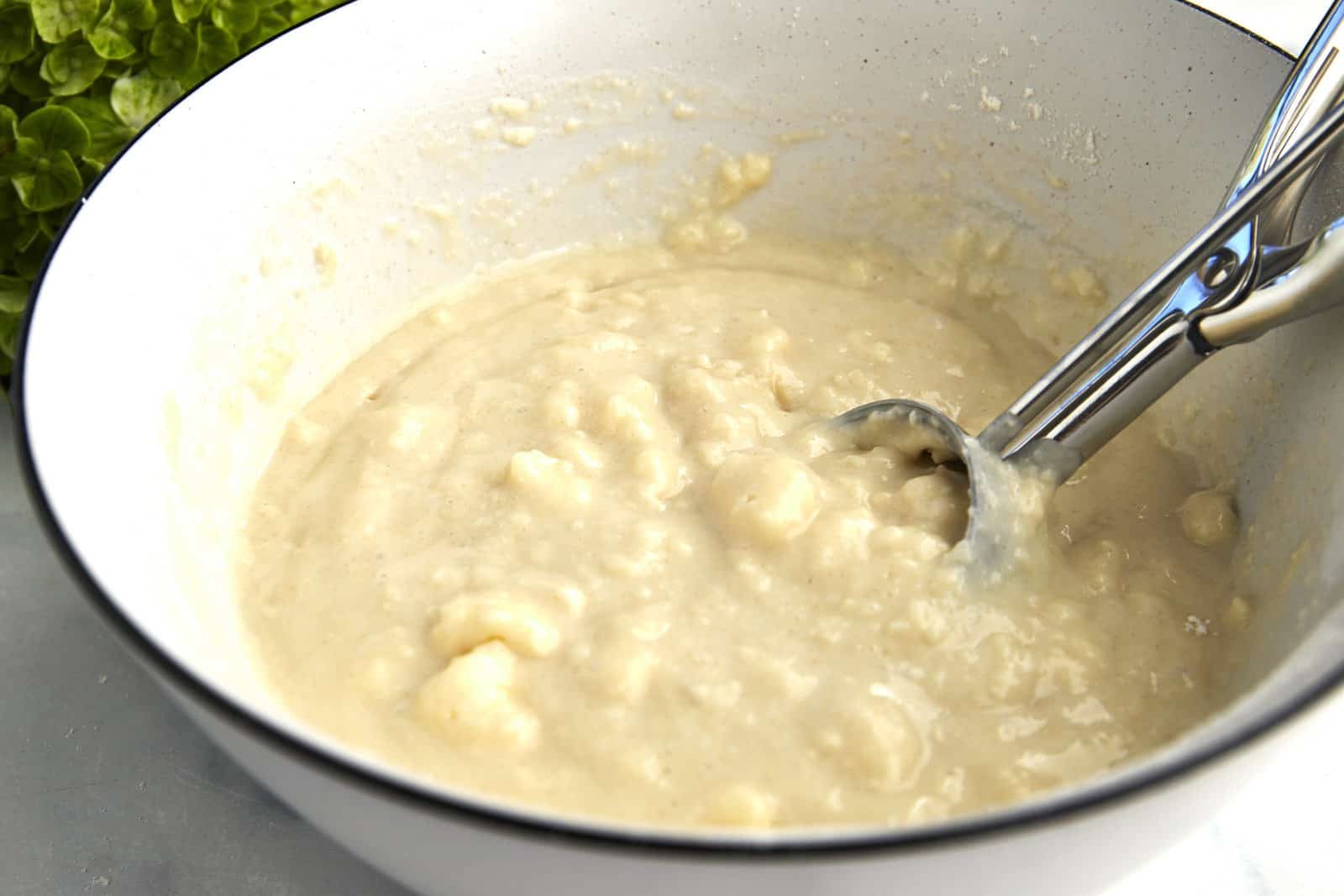 Biscuit filling in a bowl with a cookie scoop for a pear cobbler.