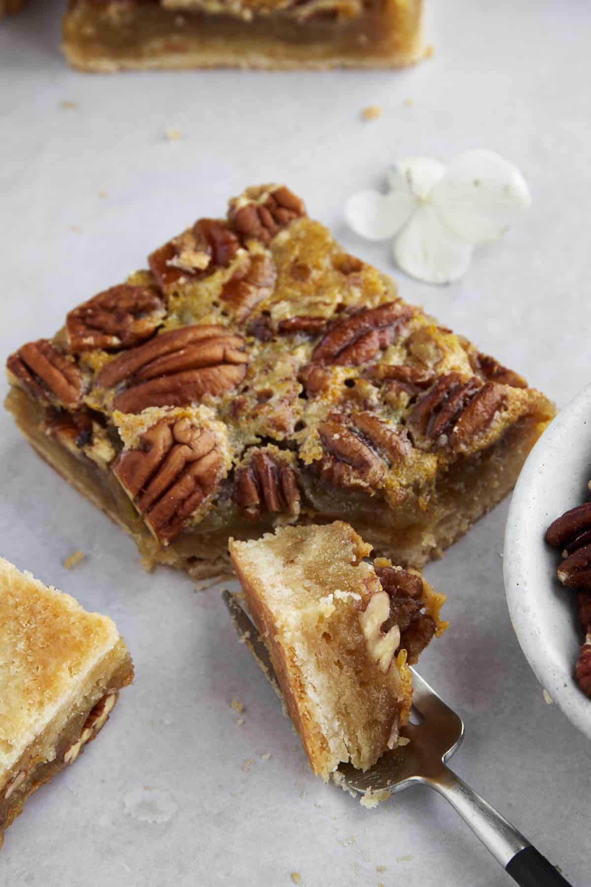 A fork taking a bite from a pecan pie bar.