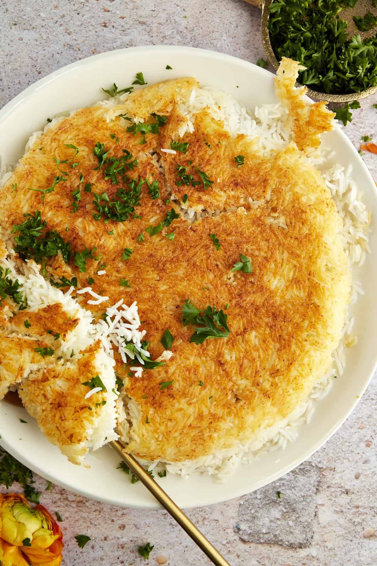 a plate of Persian rice topped with fresh herbs with a portion being scooped up