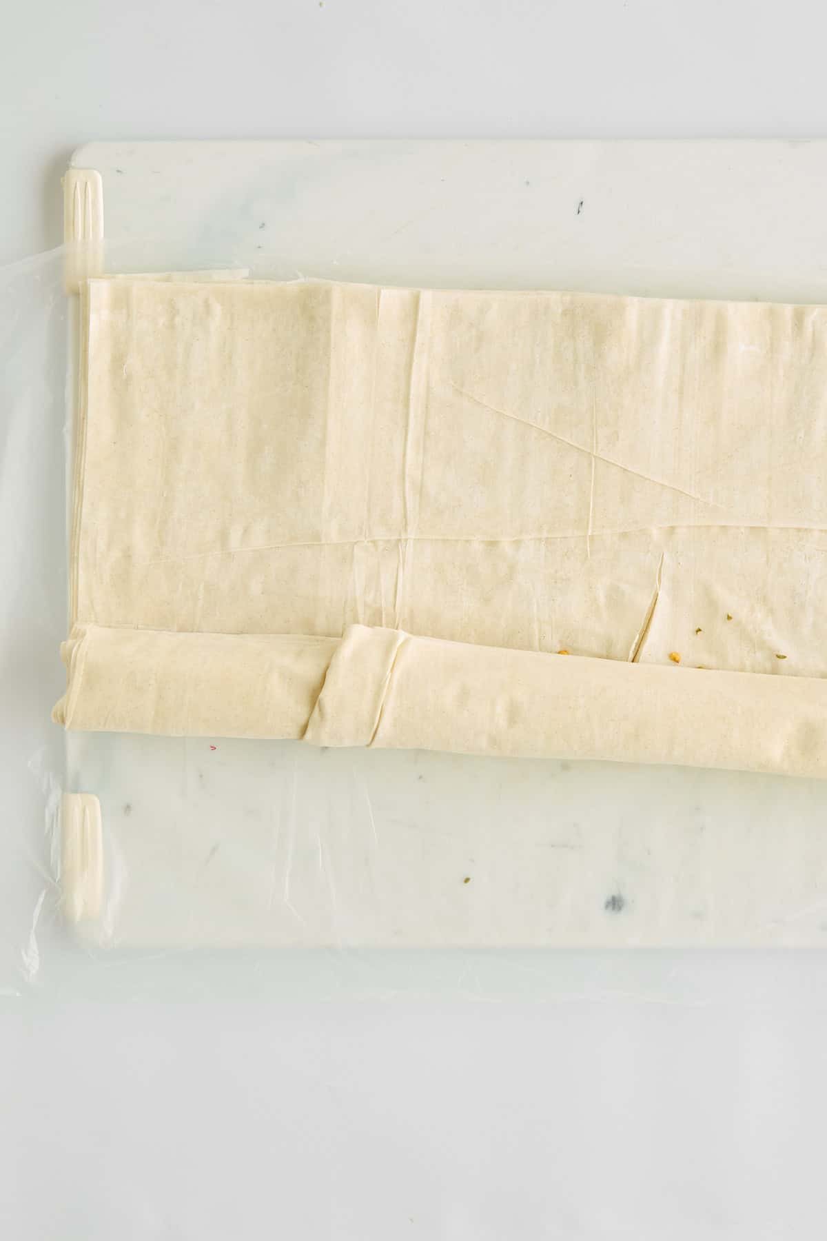Phyllo dough being rolled over hot honey feta.