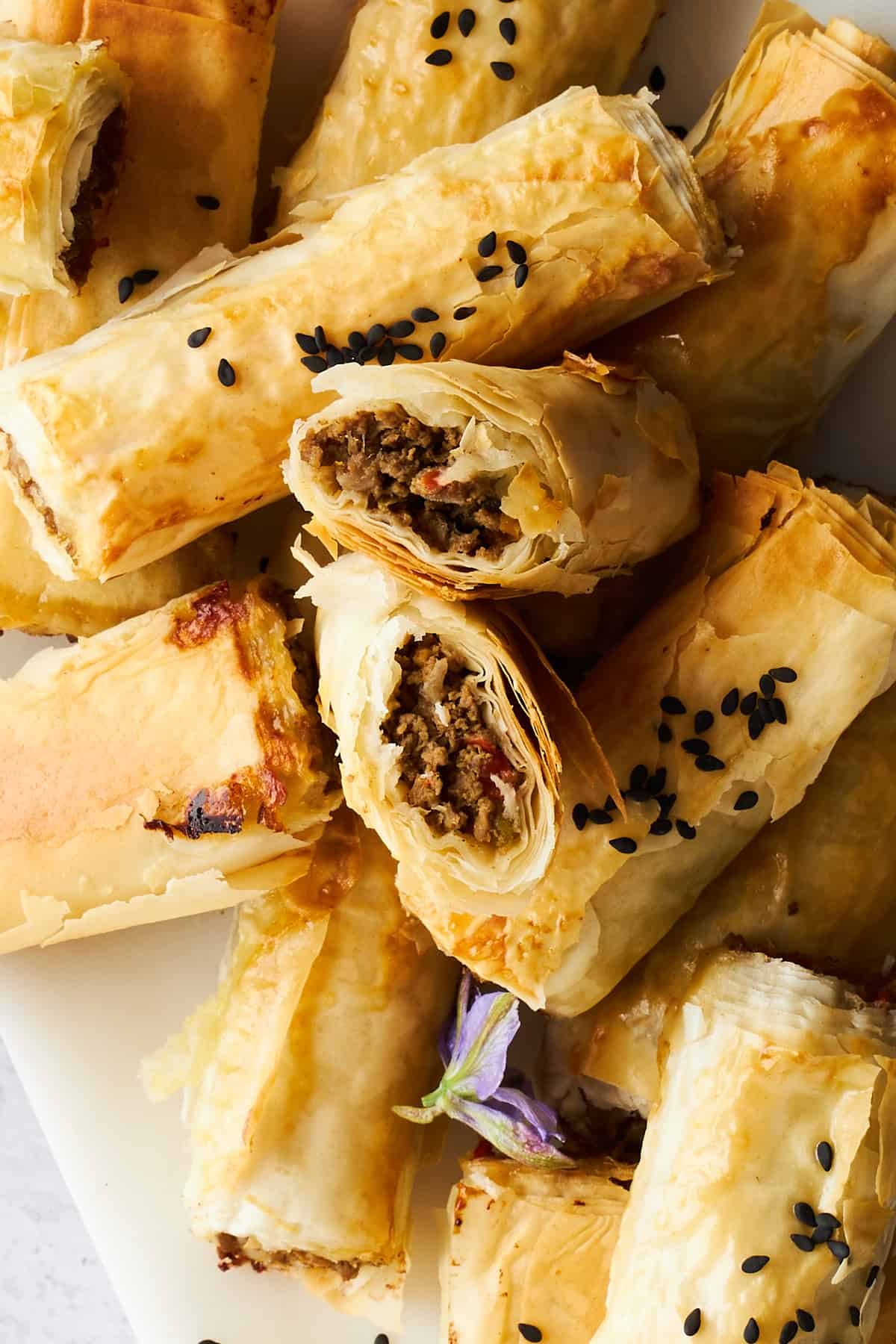 Phyllo rolls with ground beef with one split in half.