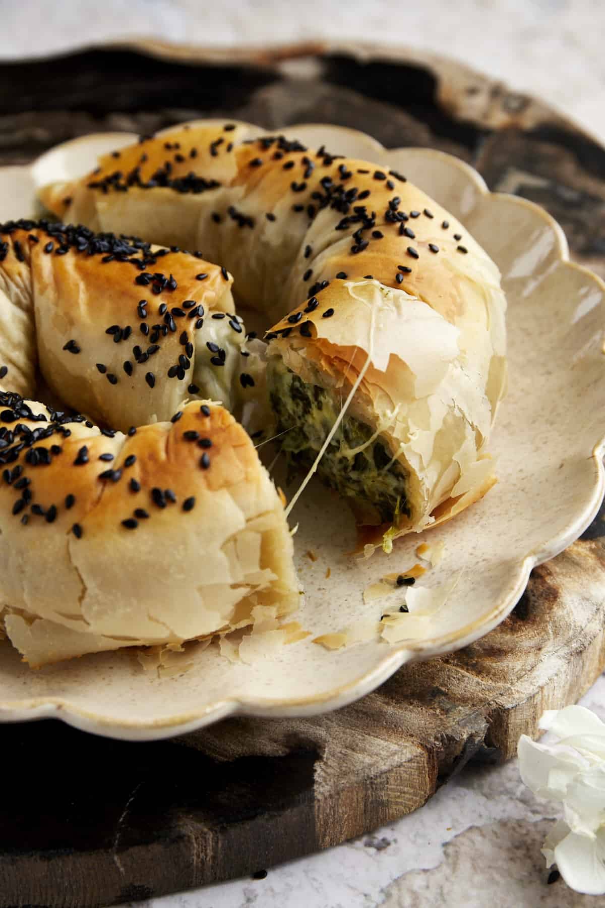 Side view of a sliced phyllo spanakopita roll exposing the cheese and spinach filling.