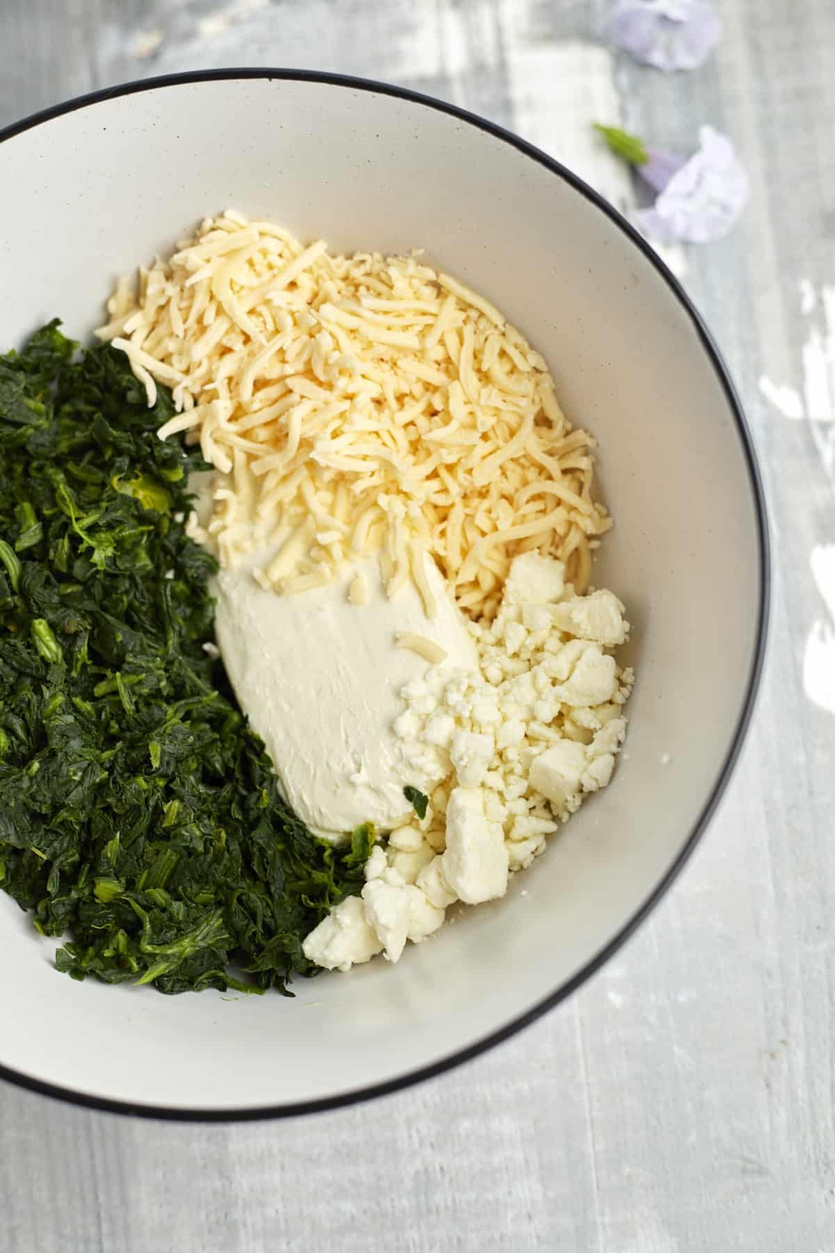 cream cheese, feta, mozzarella, and spinach in a bowl