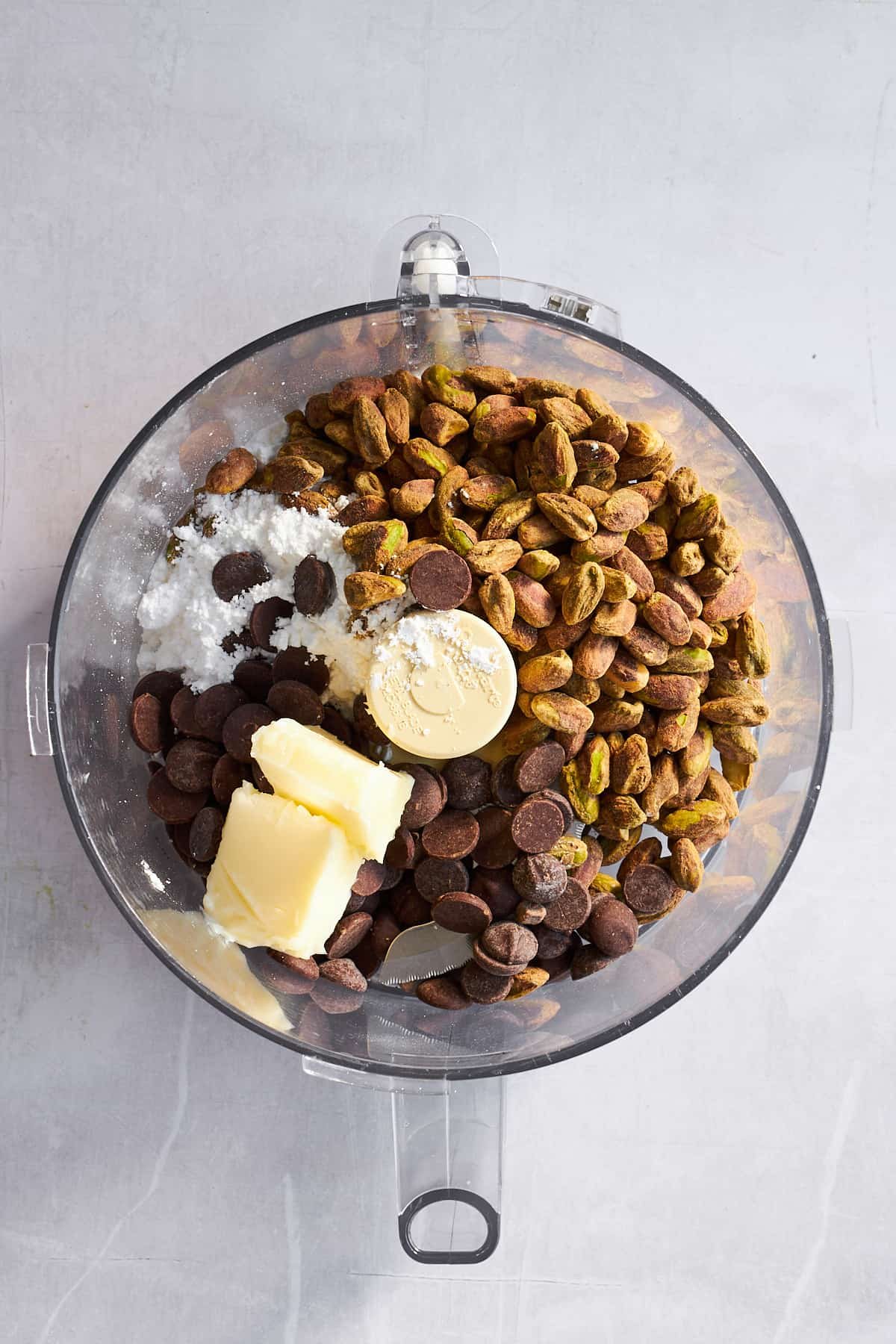 Pistachios, chocolate, powdered sugar, and butter in a food processor.