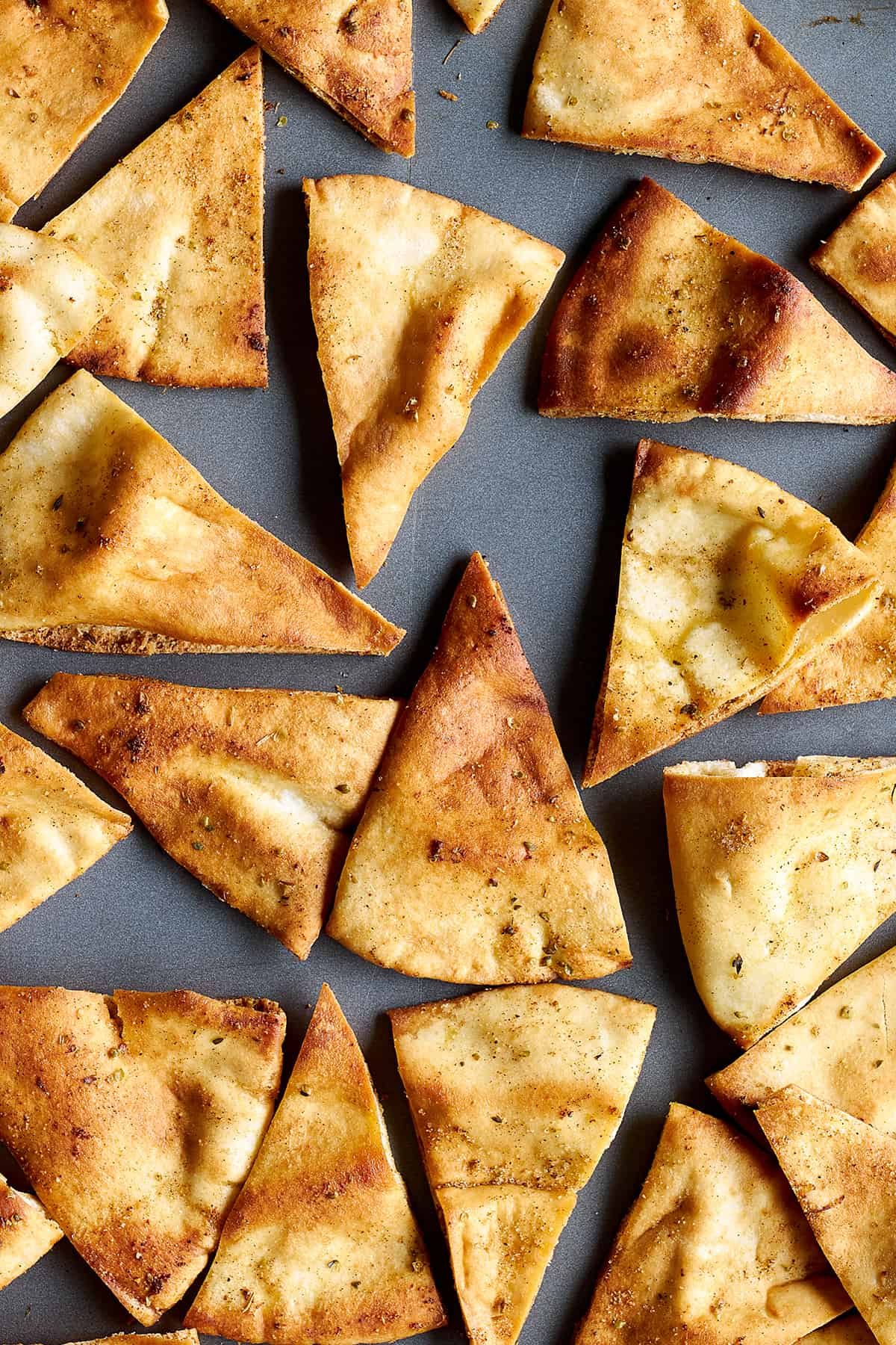 Close up view of baked pita chips on a baking sheet.