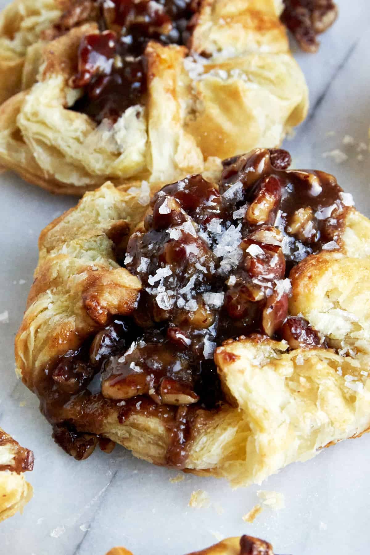 A baked handheld pecan pie dessert topped with flaky salt.