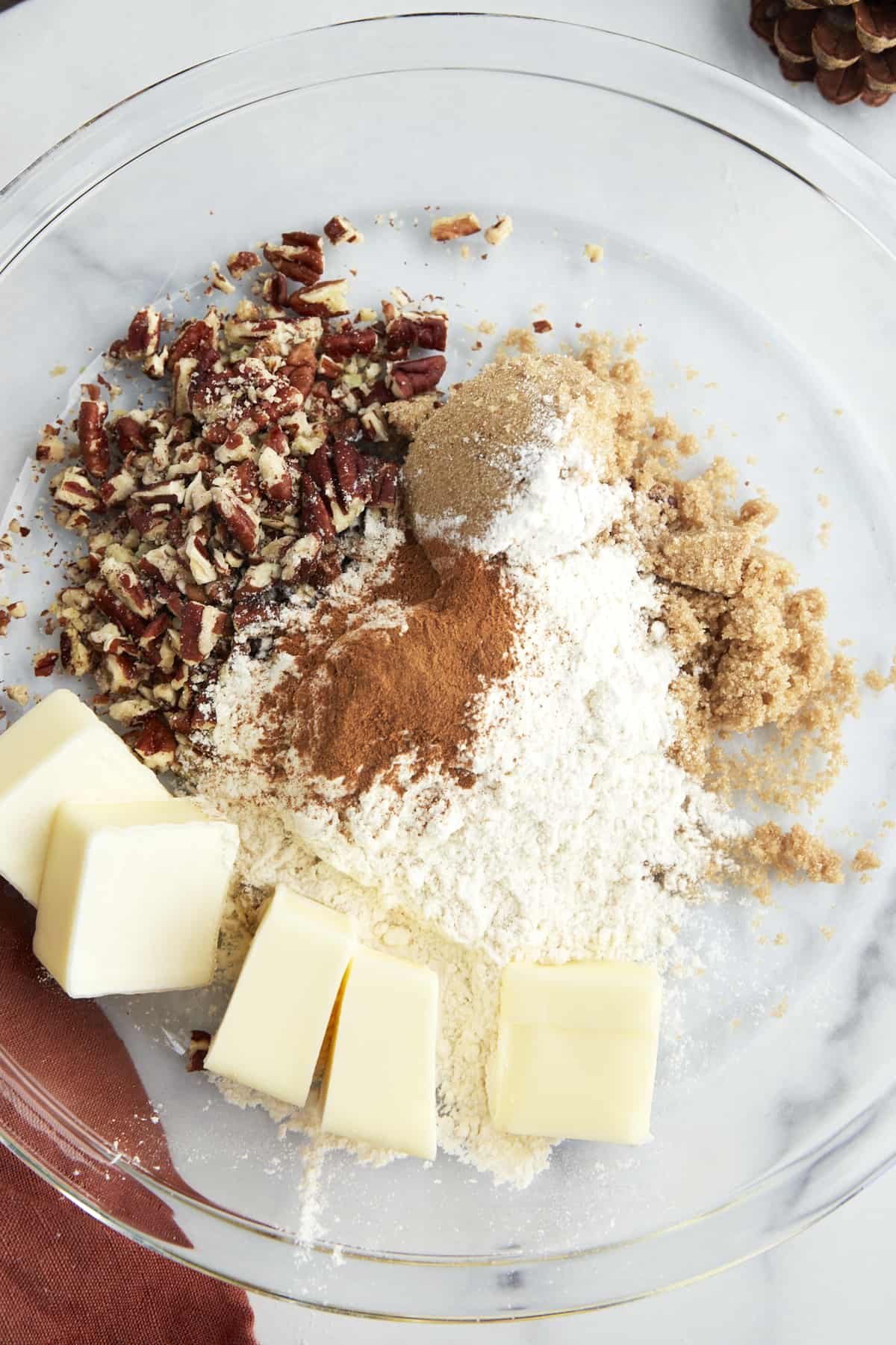 Butter, flour, brown sugar, cinnamon, and pecans in a bowl.