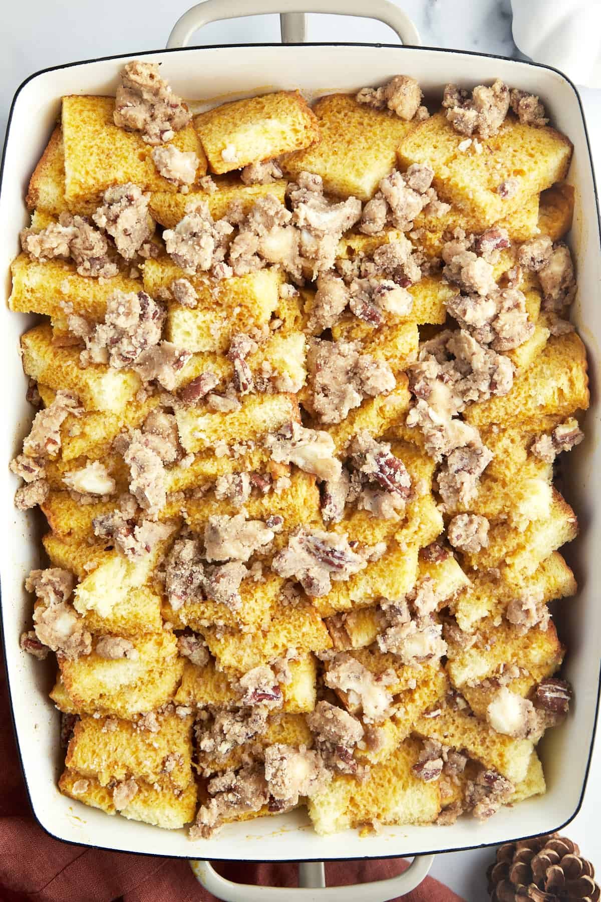 Unbaked pumpkin French toast in a baking dish topped with streusel.