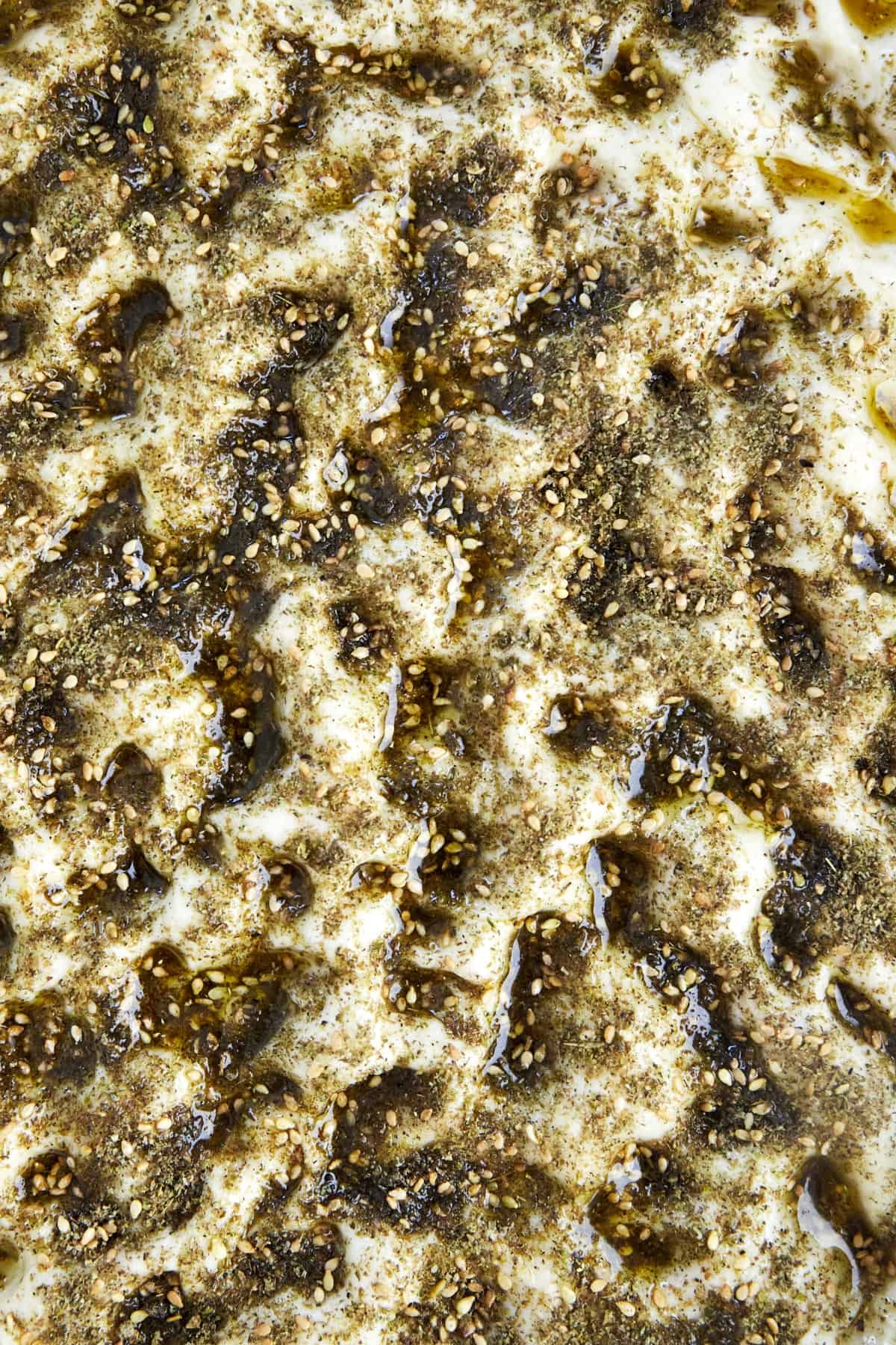 unbaked quick focaccia recipe in a baking dish topped with olive oil and za'atar