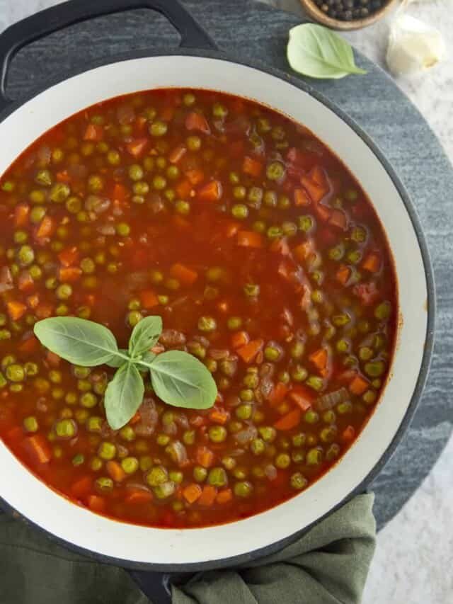 a large pot full of pea and carrot vegetarian stew topped with fresh herbs