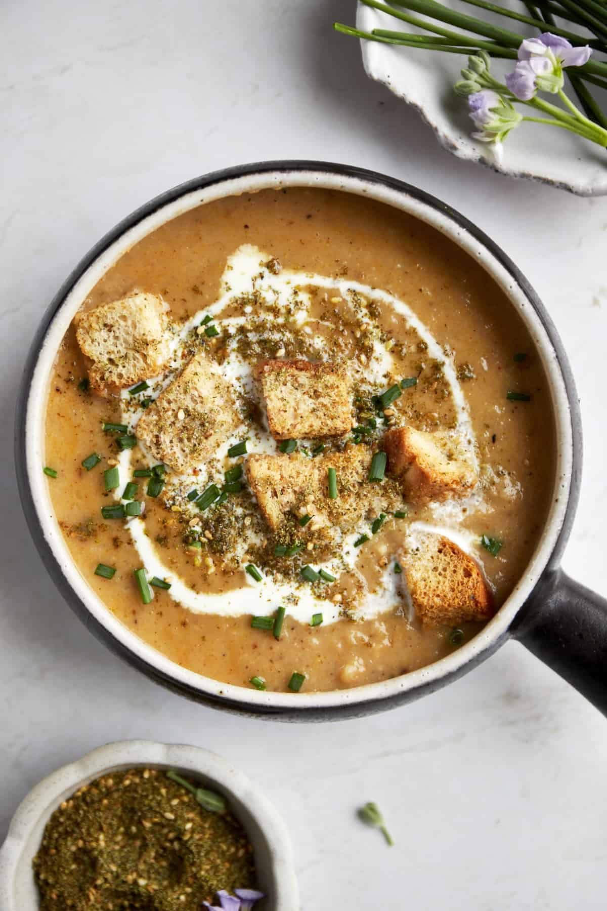 a bowl of roasted cauliflower soup topped with croutons.