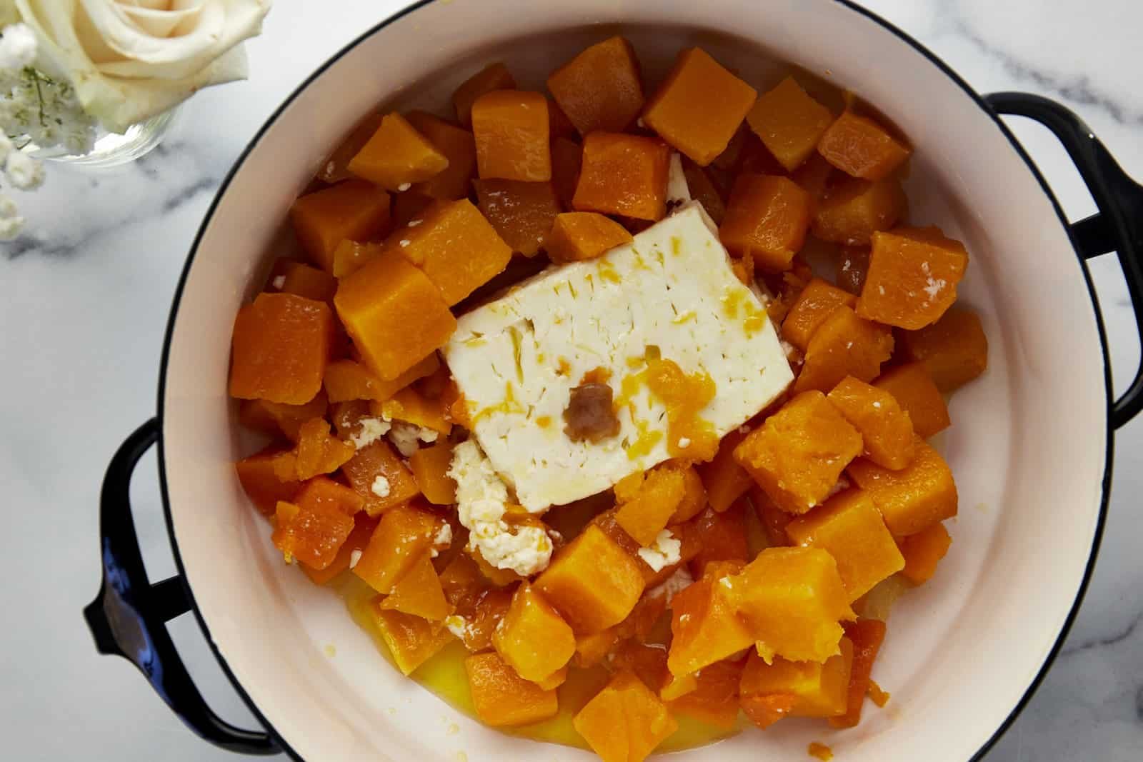 Cooked butternut squash, feta, nad garlic in a pot.
