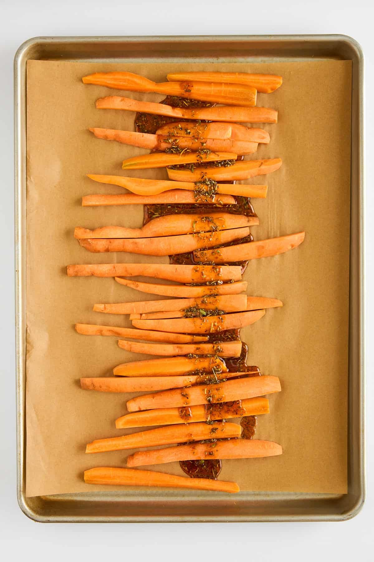 Carrot sticks on a parchment paper lined baking sheet.