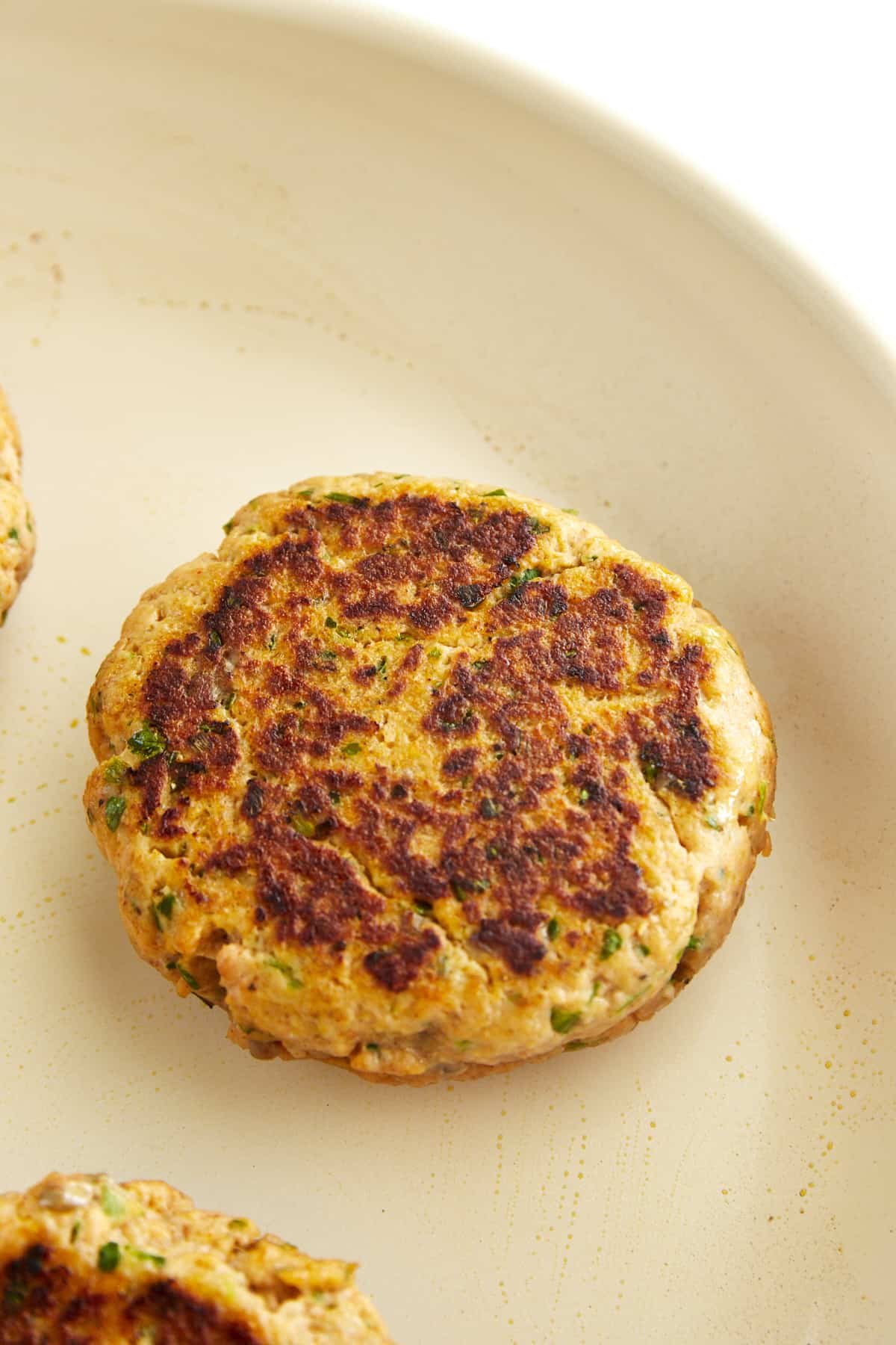 A cooked salmon burger in a skillet.