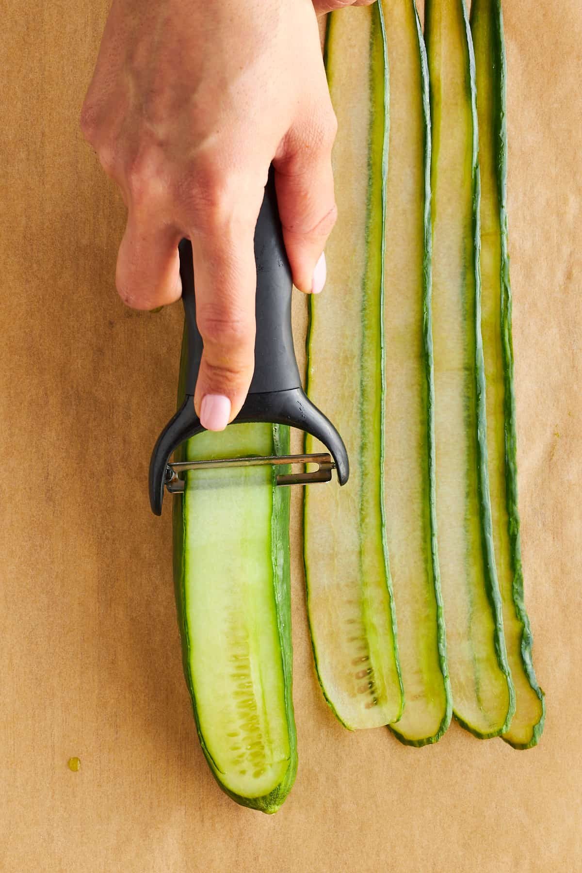 A cucumber being sliced into strips.