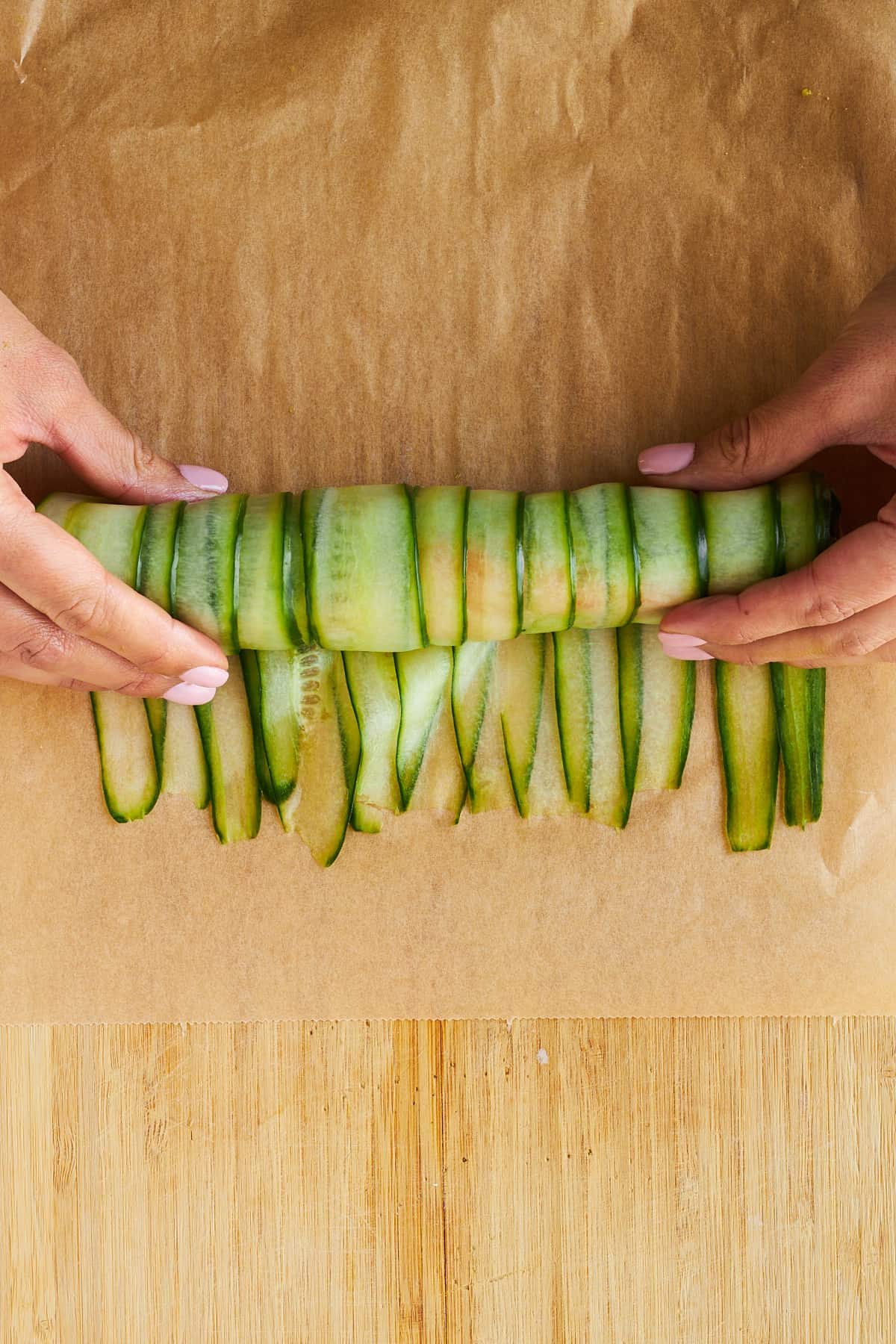 Hands rolling a cucumber roll onto itself.
