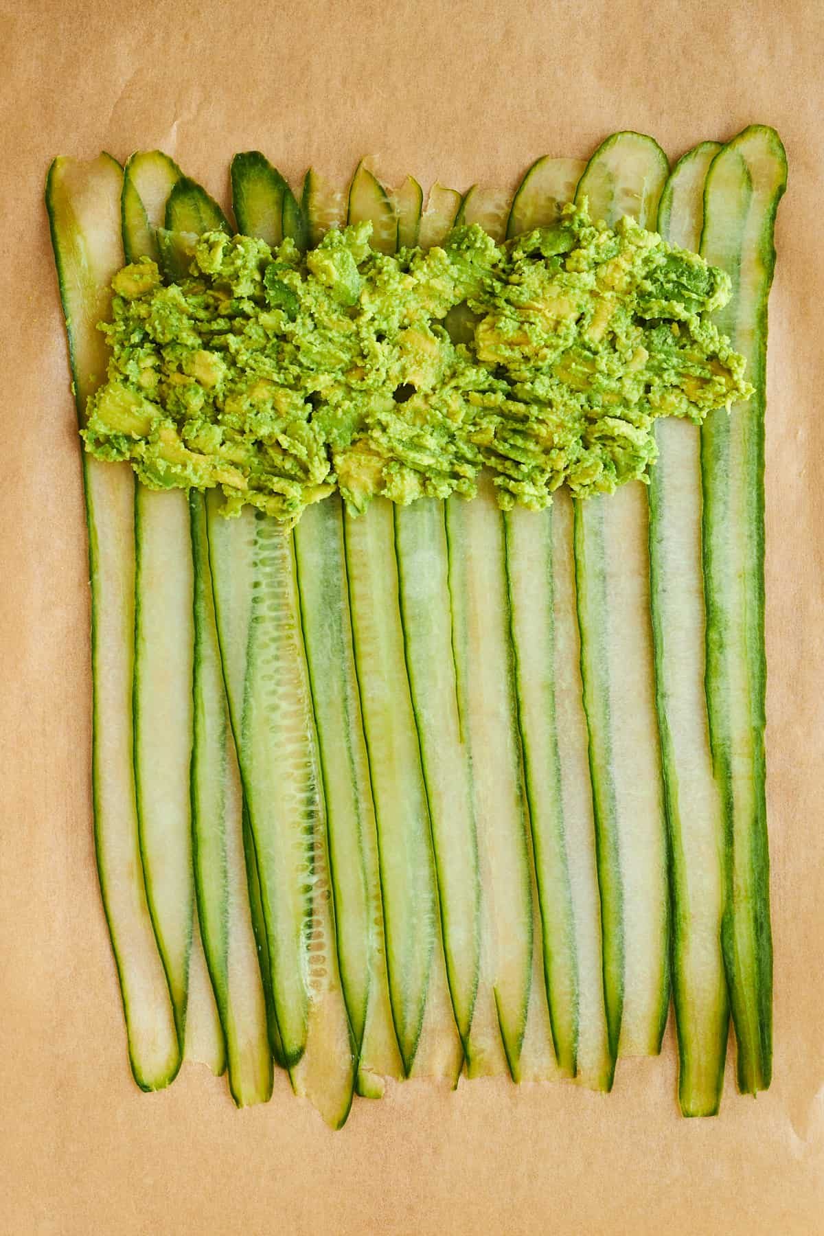 Smashed avocado layered over cucumber strips.