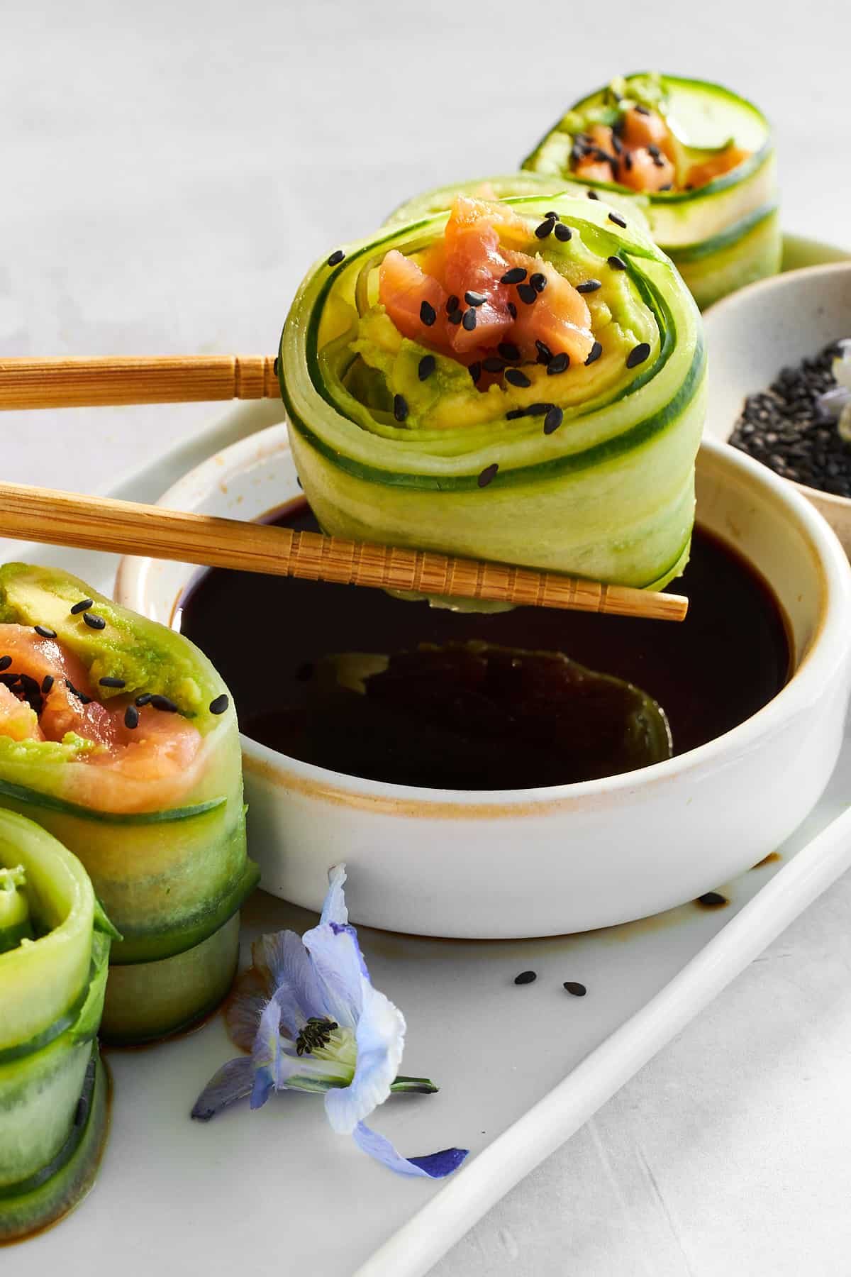 A salmon cucumber roll being dipped into soy sauce.