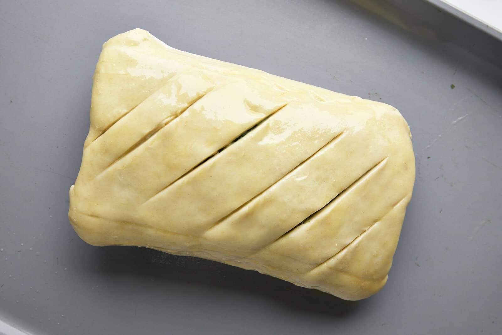 Unbaked salmon Wellington on a baking sheet.