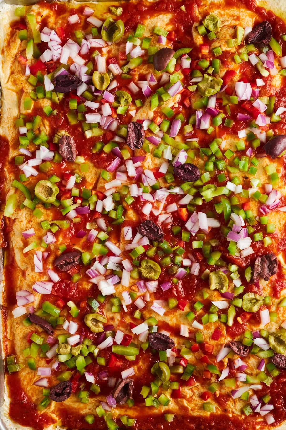 Dinner roll pizza crust topped with marinara sauce, peppers, onions, and olives.