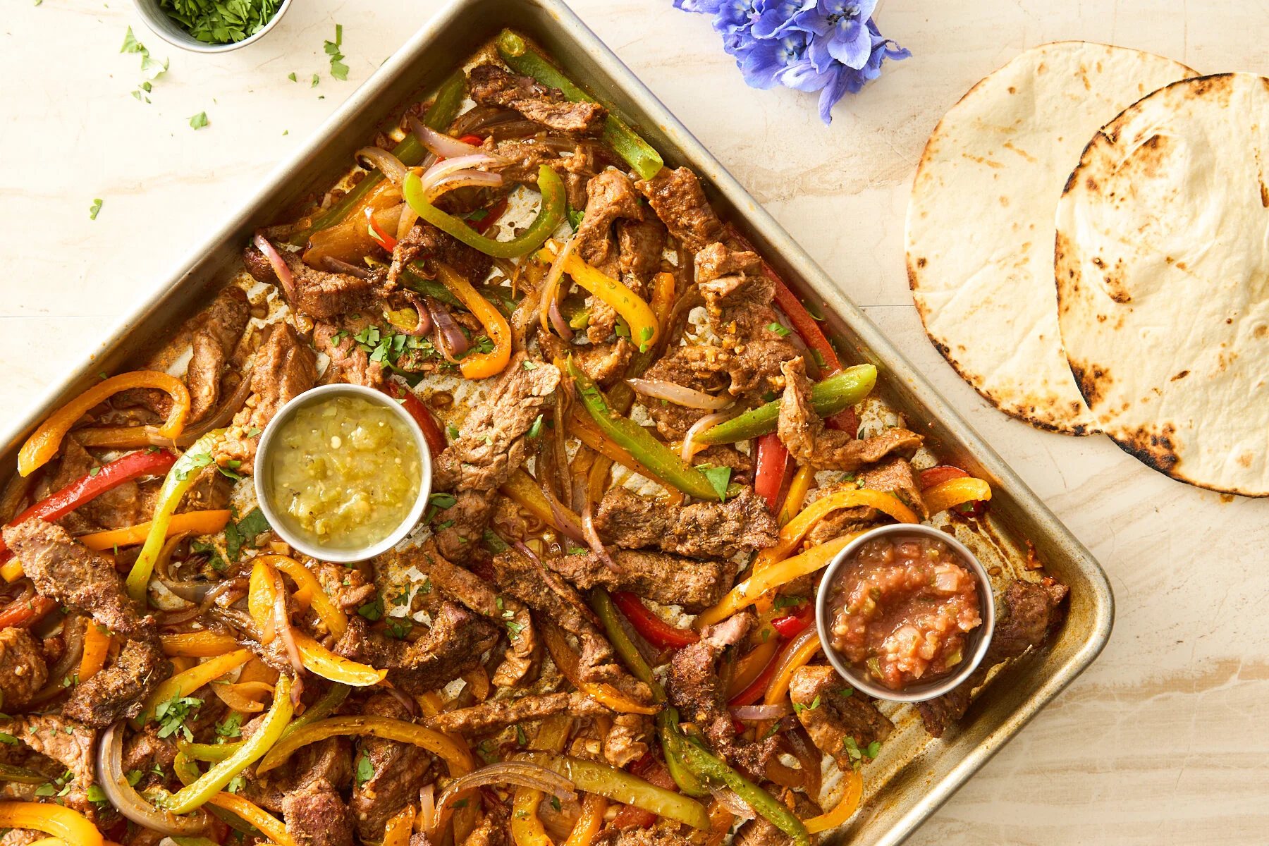 Sheet pan steak fajitas on a baking sheet.