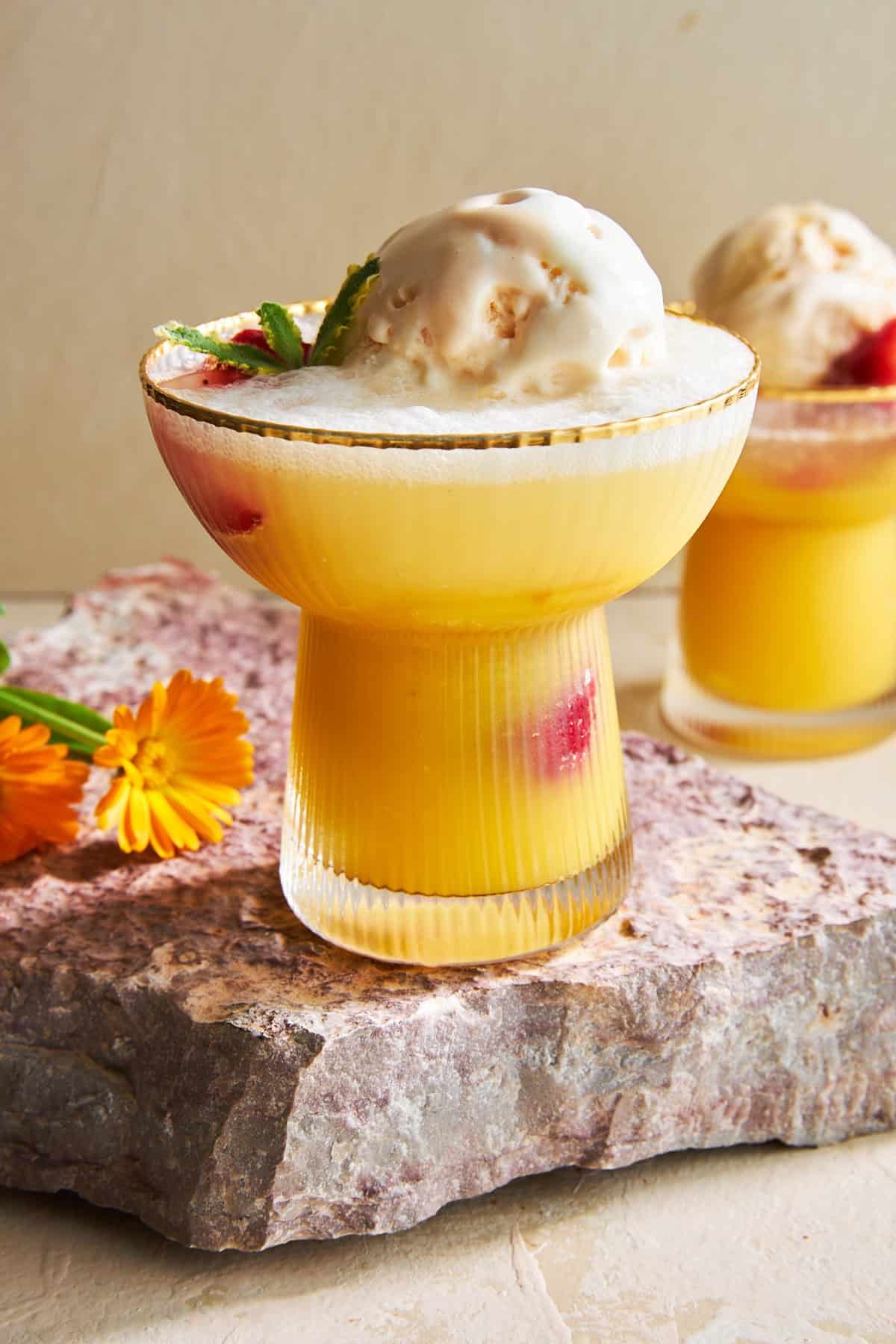 Two glasses of sherbert punch with ice cream and strawberries.