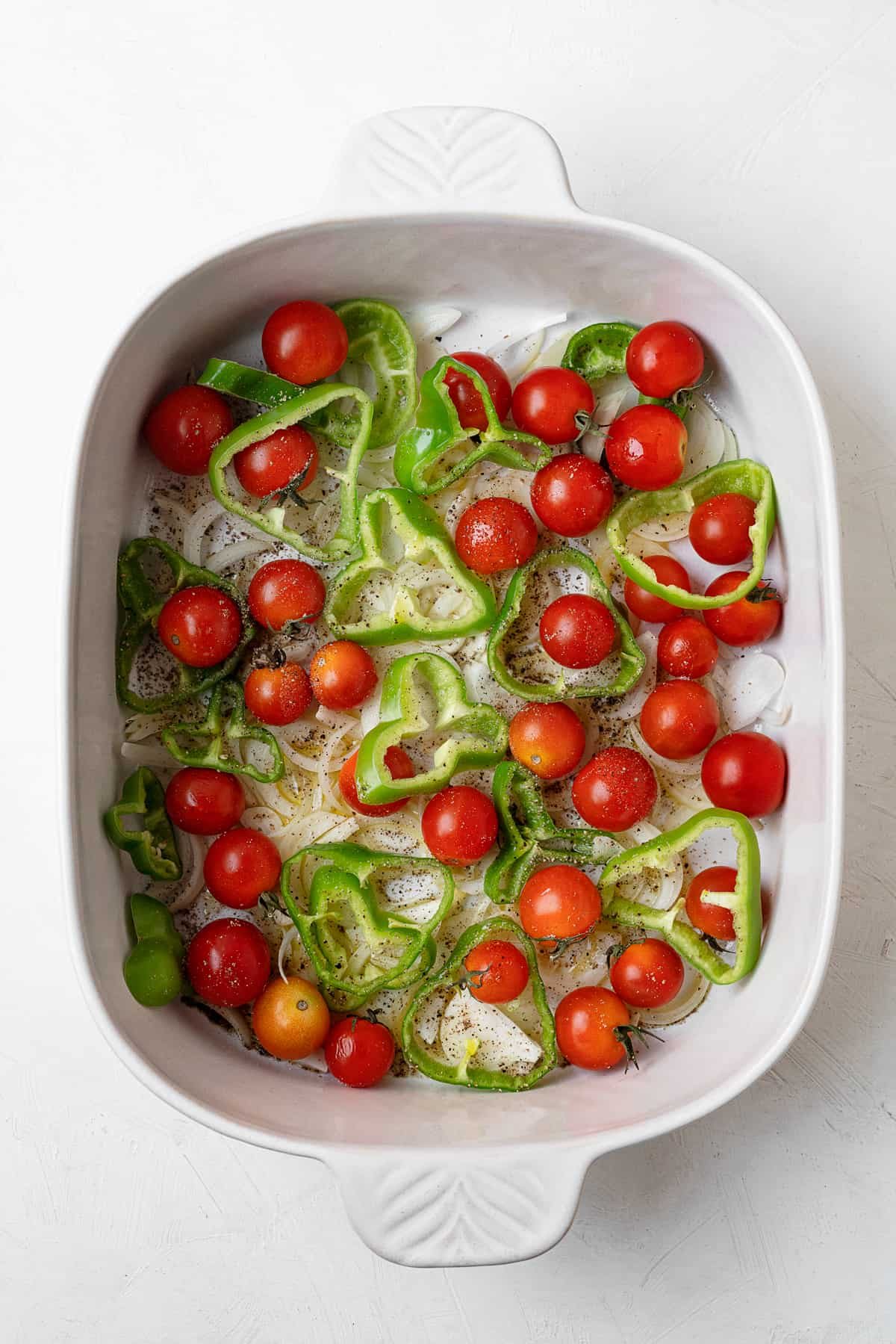 overhead baking dish with tomatoes peppers and seasoning