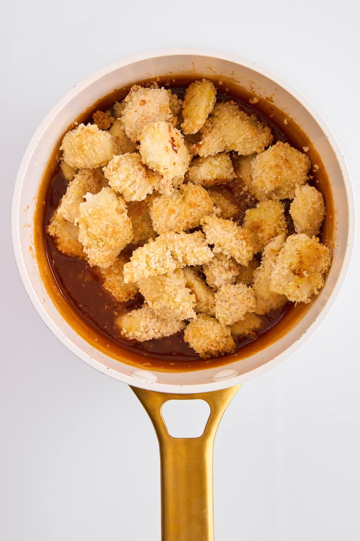 Breaded cooked chicken pieces in a pot of orange chicken.