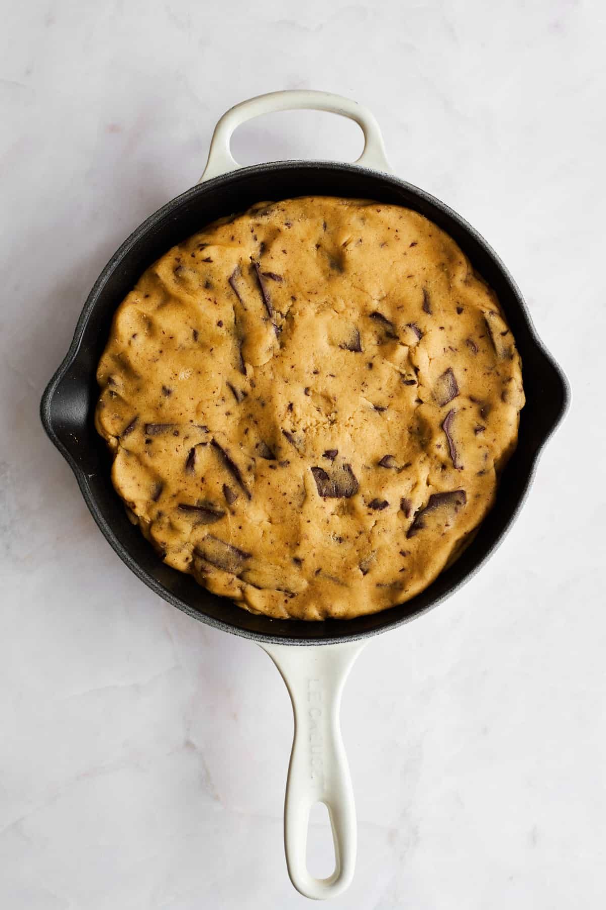 Raw chocolate chip cookie dough in a skillet.