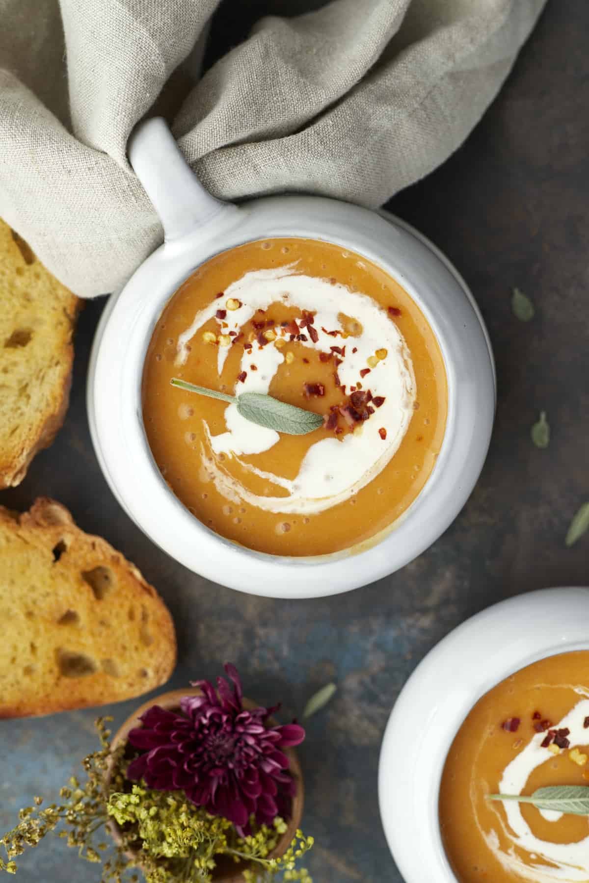 overhead image of a bowl of simple butternut squash soup with bread pieces around.
