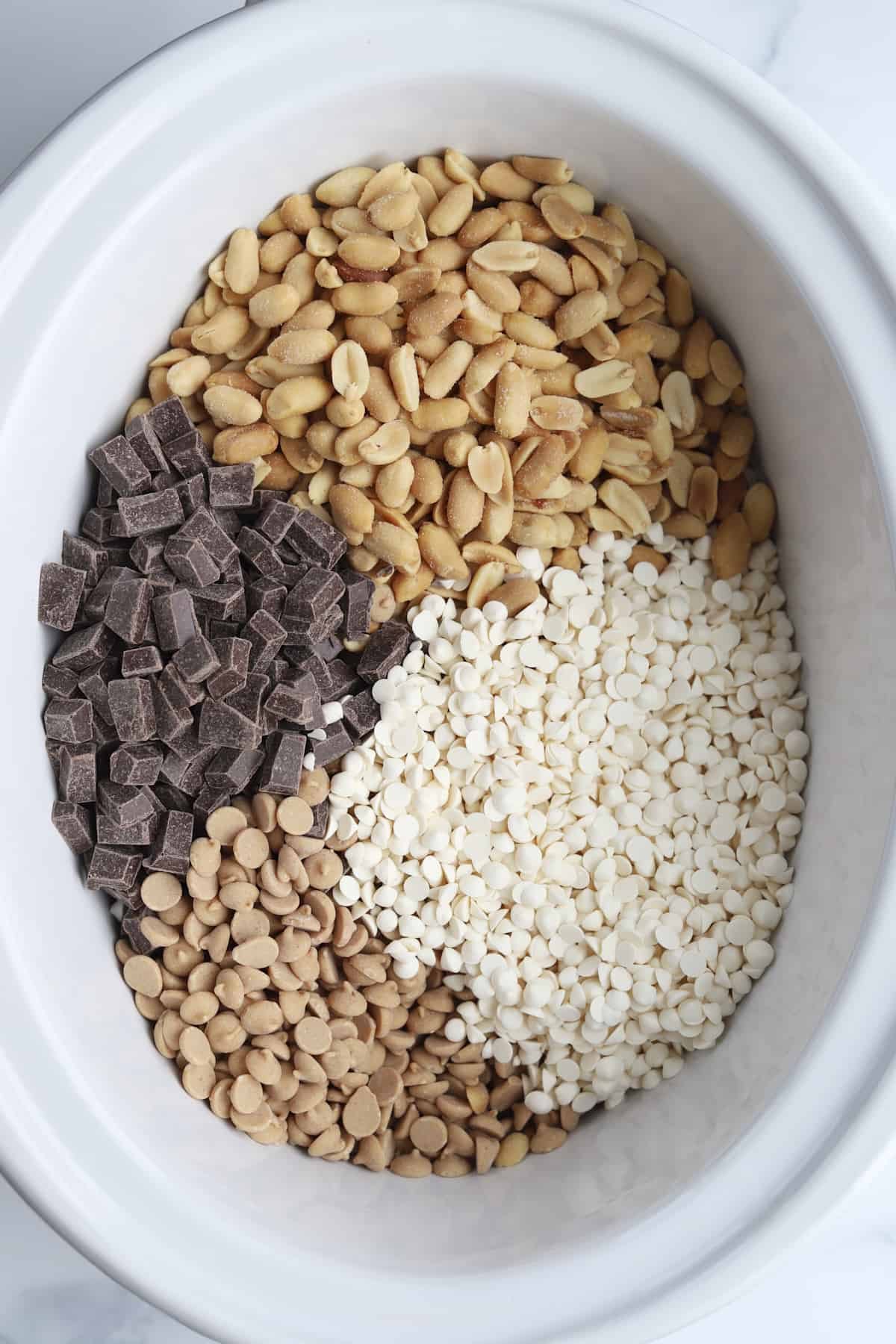 peanuts, white chocolate chips, dark chocolate chunks, and peanut butter chips in a slow cooker