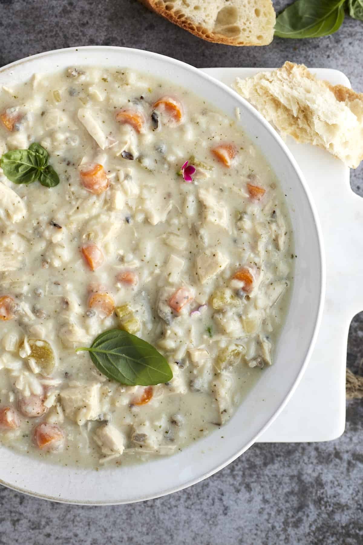 creamy chicken wild rice soup in a bowl with a chunk of bread on the side