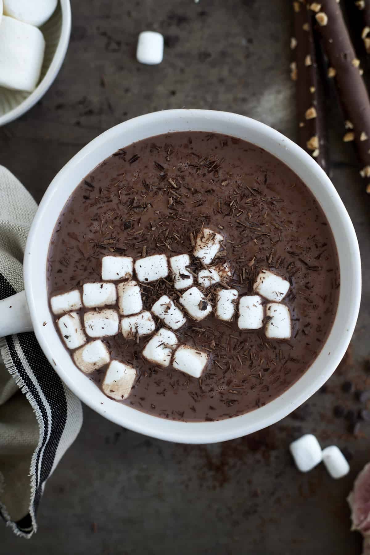 A mug of hot chocolate with espresso topped with chocolate shavings and marshmallows.