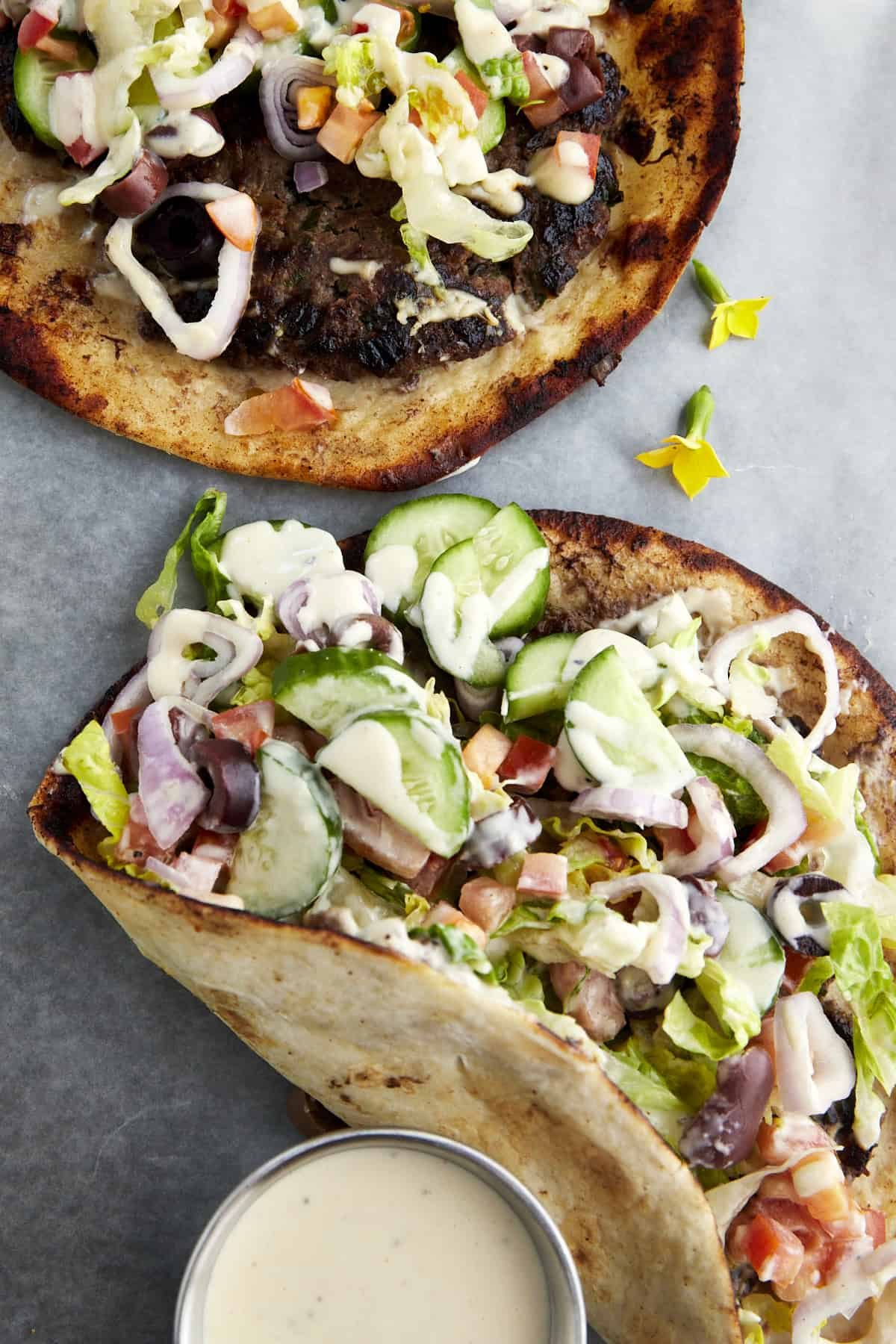 Two Greek-inspired smashed tacos with a side of tahini.