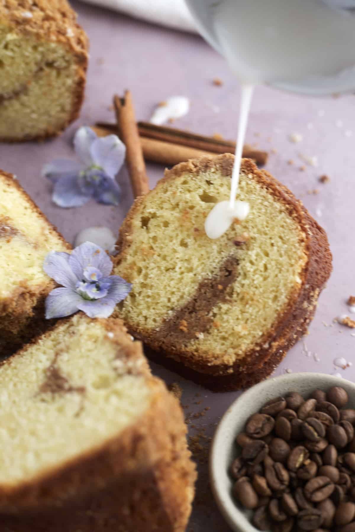 a slice of sour cream coffee cake with glaze being drizzled on top