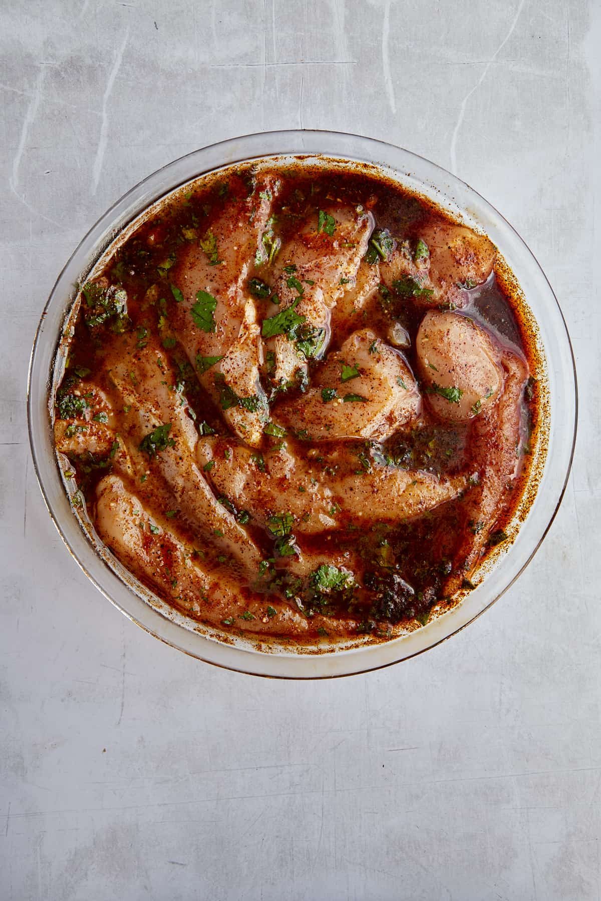 raw chicken marinading in a bowl.