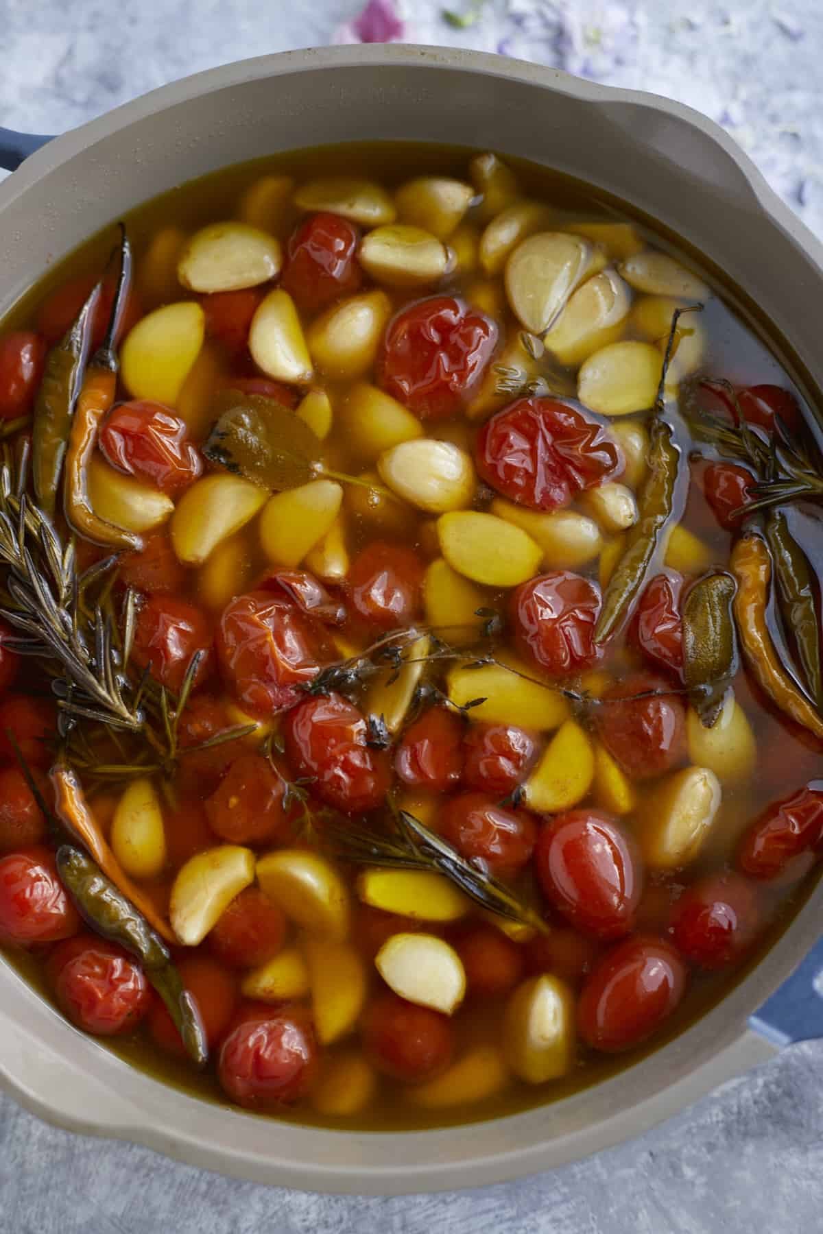 overhead pan with tomatoes, chili peppers, garlic, herbs, in olive oil
