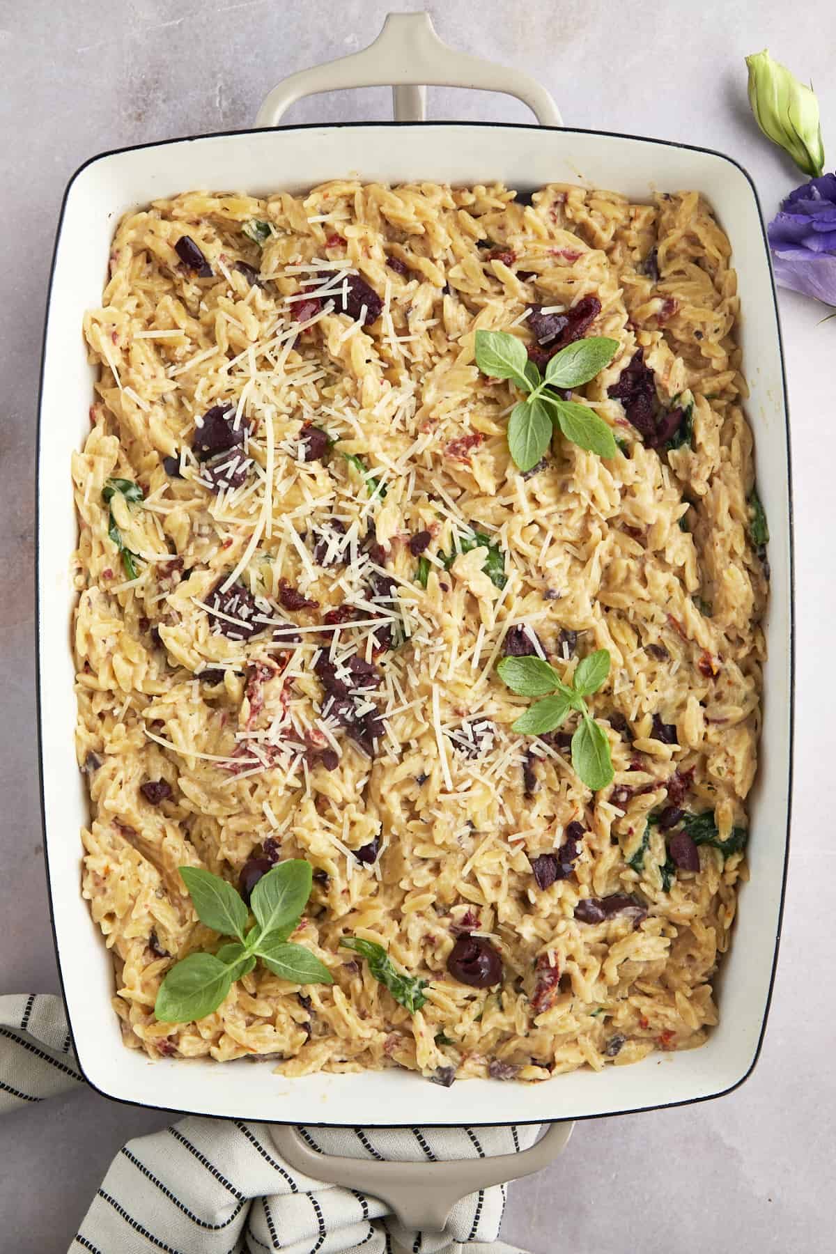 A baking dish full of spinach and sun-dried tomato boursin orzo bake.