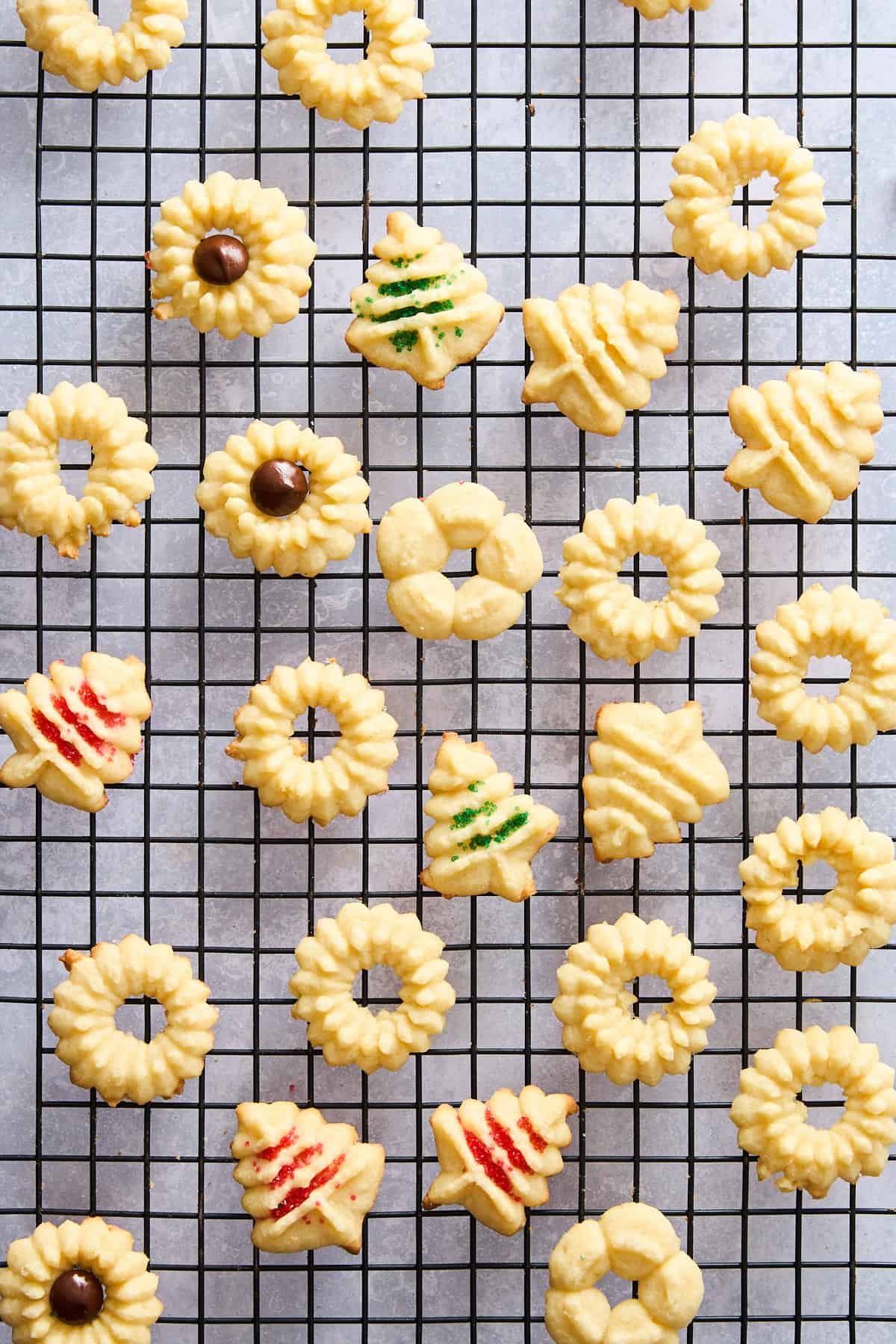Spritz cookies in different shapes on a wire rack.