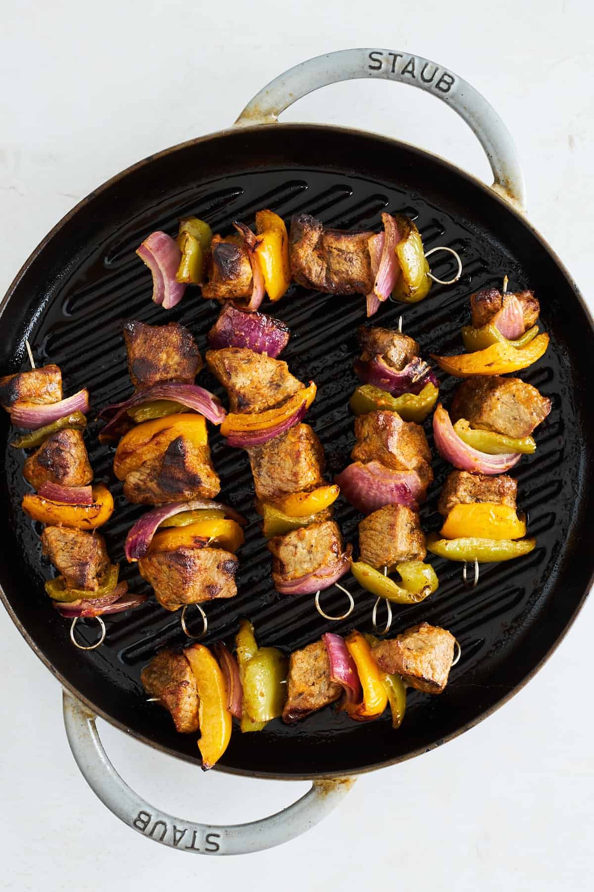 Steak skewers coking on a grill pan.