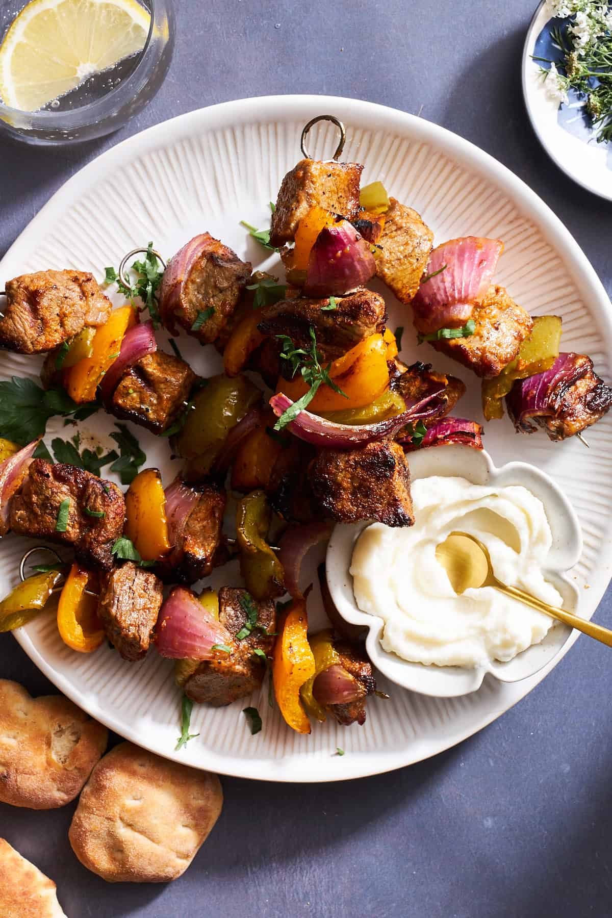 A plate of grilled steak skewers with peppers and onions.