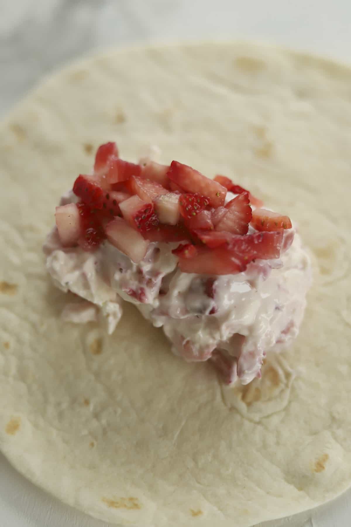 a tortilla shell with a strawberry cream cheese mixture in the center
