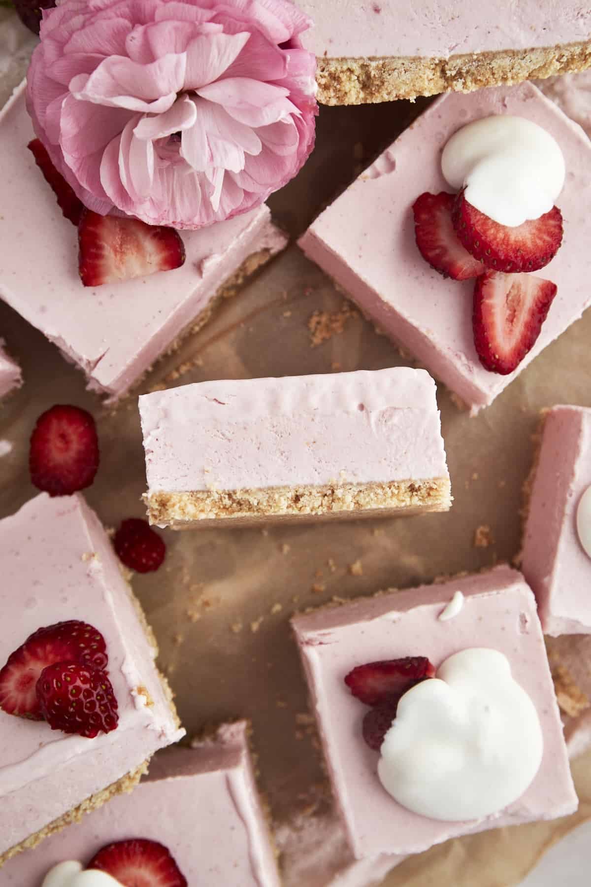 No-bake strawberry cheesecake squares topped with strawberries and whipped cream.