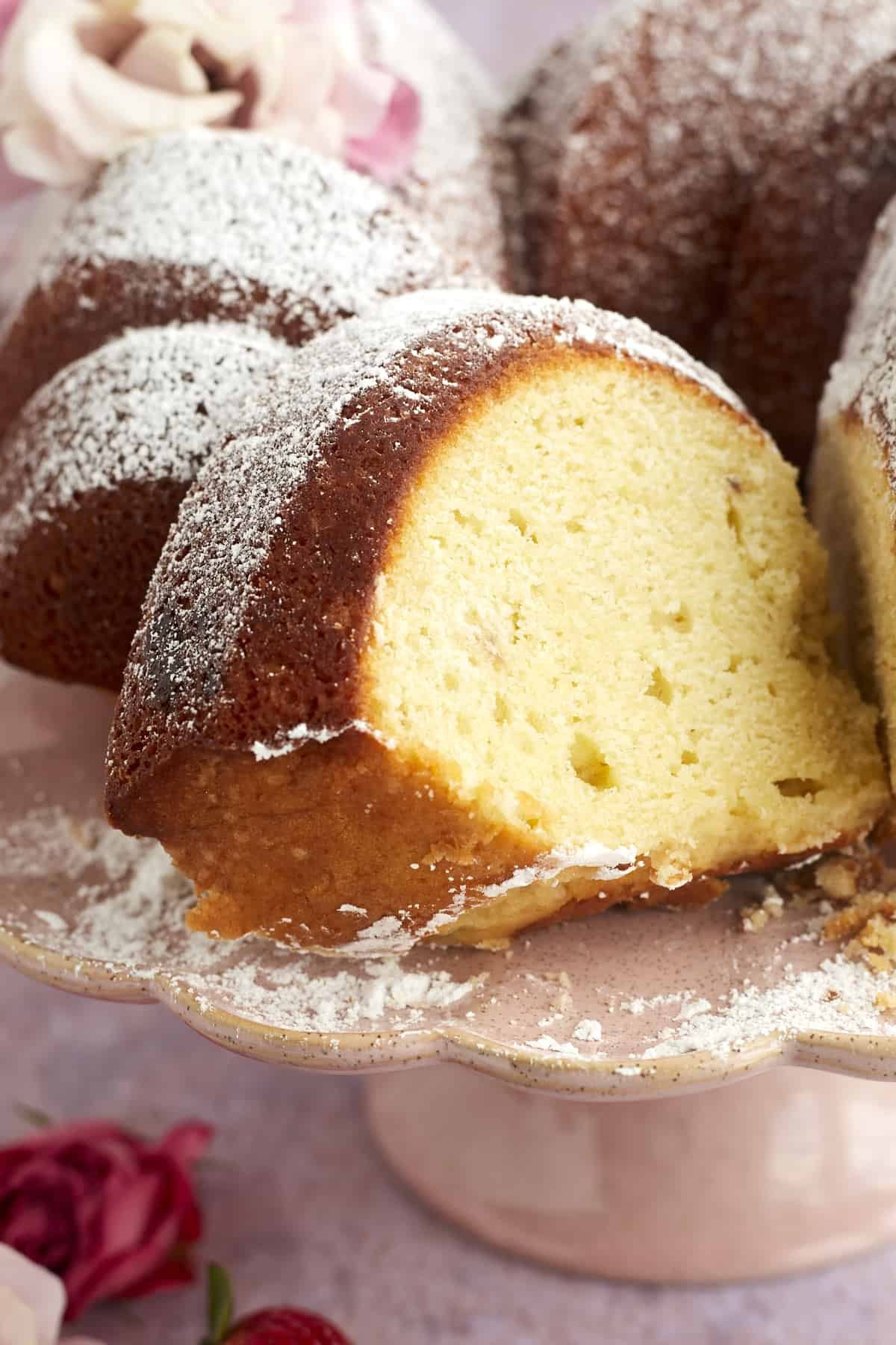 close up image of a slice of strawberry lemon bundt cake topped with powdered sugar