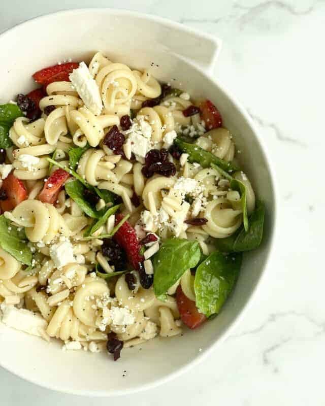 A bowl of summer pasta salad with fruit.