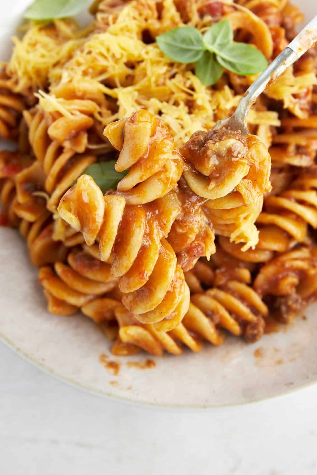 A fork holding a bite of taco pasta with beef.