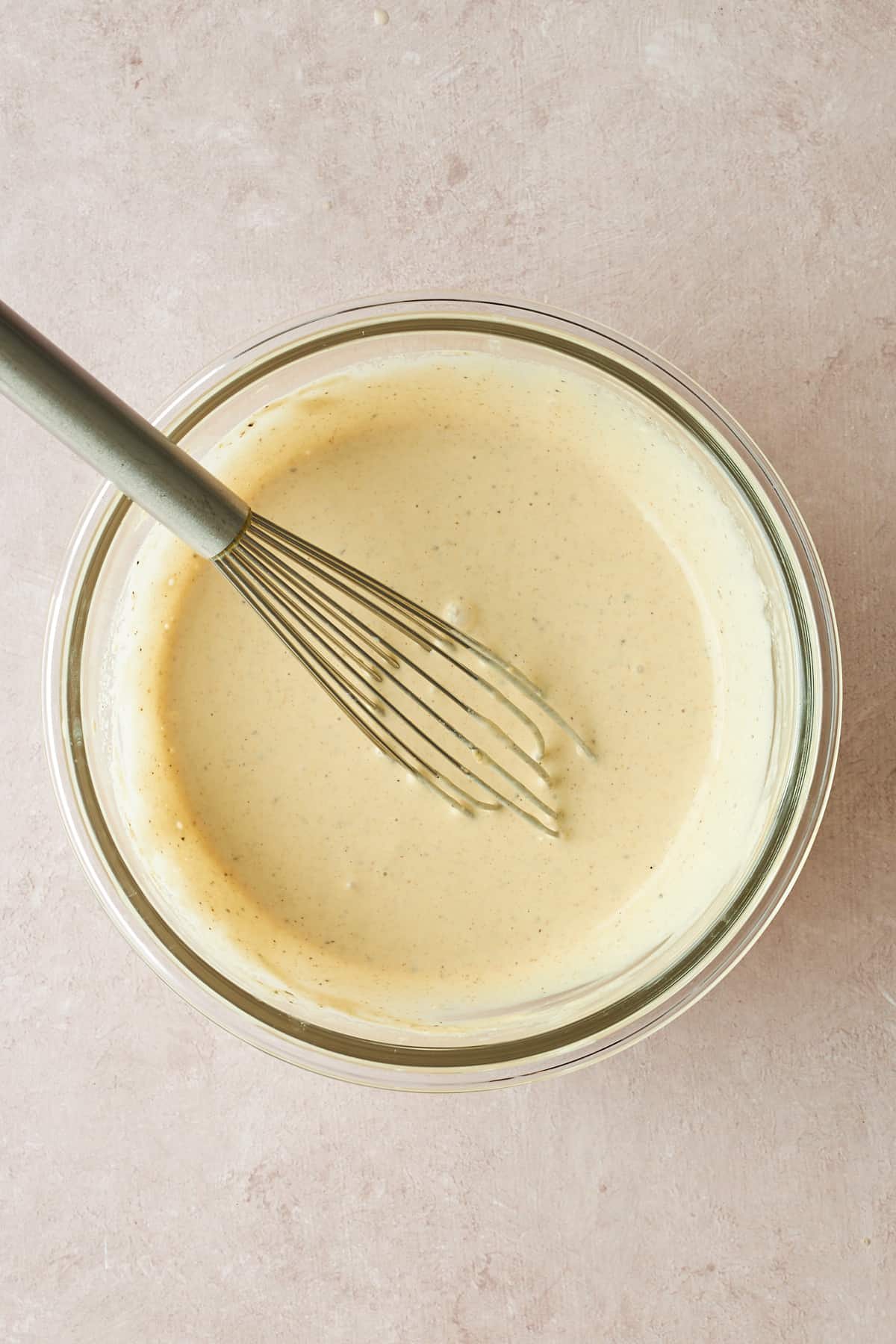 A bowl of tahini dressing with a whisk sticking out.