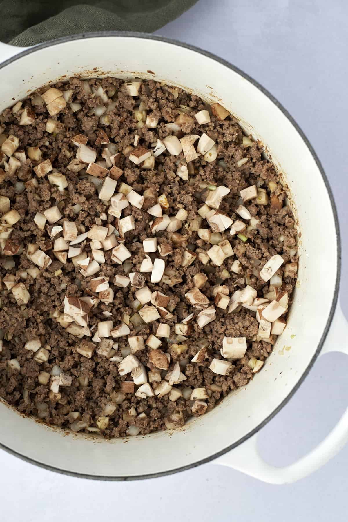 browned ground beef, onions, and mushrooms in a pot to make a tater tot hotdish recipe